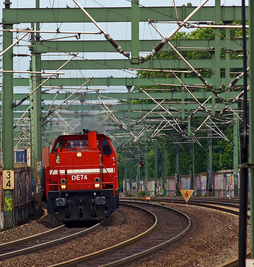 Durch den Gleisbogen kommt die DE 74 (272 012-2) der HGK (H�fen und G�terverkehr K�ln AG) ex KBE DE 84 und zieht am 03.07.2013 beim Bahnhof K�ln-Ehrenfeld einen Containerzug in Richtung Aachen.

Sie ist eine dieselelektrische Lokomotive vom Typ MaK DE 1002 und wurde 1986 bei MaK unter der Fabriknummer 1000836 gebaut und an die KBE (K�ln-Bonner Eisenbahn), 1992, bei der Verschmelzung zur HGK, umbezeichnung in HGK DE 74. Sie tr�gt die NVR-Nummer 98 80 0272 012-2 D-HGK und EBA-Nummer EBA 01K14A 074.