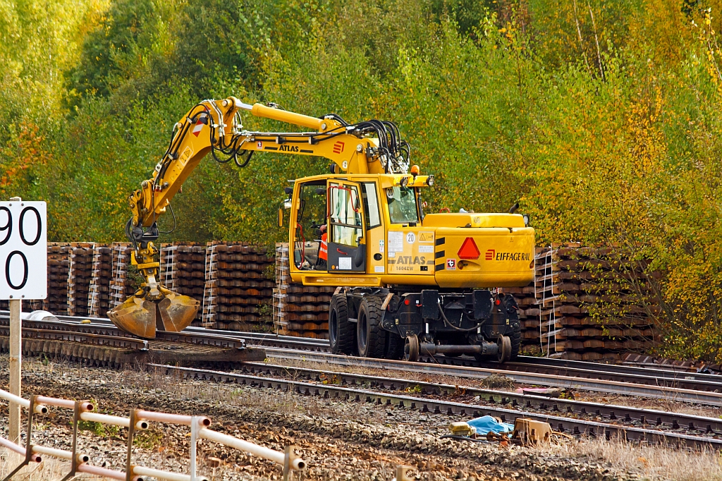 
Gleisbaustelle Bf. Herdorf am 13.10.2012 (Erneuerung Gleis 2) - Arbeiter l�sen die Schienenbefestigungen, zuvor wurden die Schienen durchgebrannt und das komplette Gleis in Segmenten auf Gleis 3 abgelegt. Mit einem Zweiwegebagger werden Schwellen beiseite gelegt.