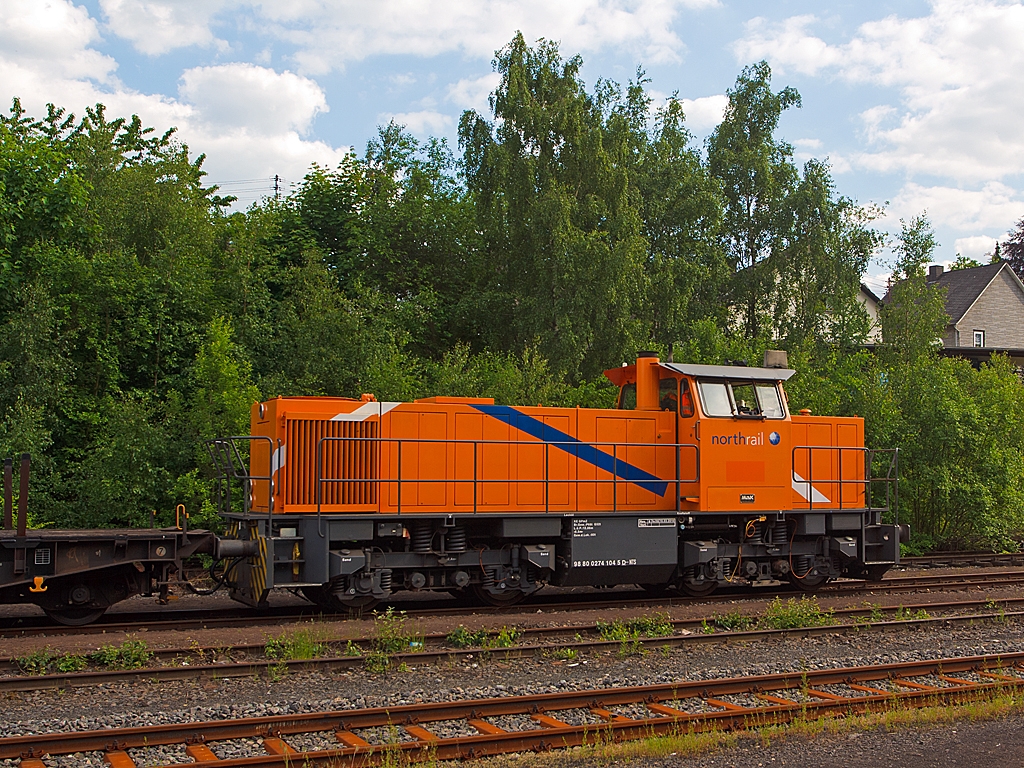 Im Bahnhof Herdorf hat am 06.06.2013 auf Gleis 4 die MaK G 1205 der northrail 274 104-5 (98 80 0274 104-5 D-NTS) mit leeren Sammnps-Schwerlastwagen noch Hp 0, bevor sie Richtung Betzdorf weiterfahren kann.
Die Lok wurde 1993 bei Mak in Kiel unter der Fabriknummer 1000892 f�r Bayernwerk AG (BAG), Schwandorf  M 22 gebaut. Im Jahr 2002 kam sie dann zur OHE - Osthannoversche Eisenbahnen AG, Celle als  150007 , bis sie 2009 zur northrail kam.
