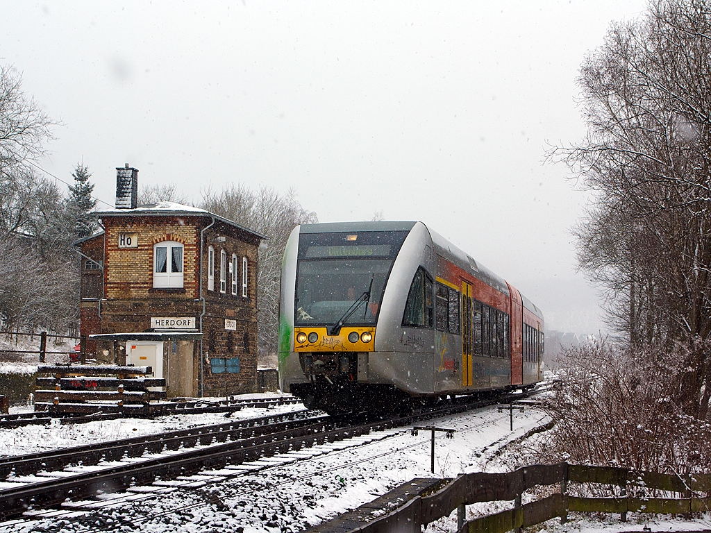 Und wieder, wie mein Freund Stefan es nennt, l�sst der Winter seinen Abfall fallen - 
Ein Stadler GTW 2/6 (VT 118) der Hellertalbahn f�hrt am 17.03.2013, bei Schneefall, von Herdorf weiter in Richtung Neunkirchen. 

Links ist das 1901 gebaute Stellwerk Herdorf Ost (Ho).
