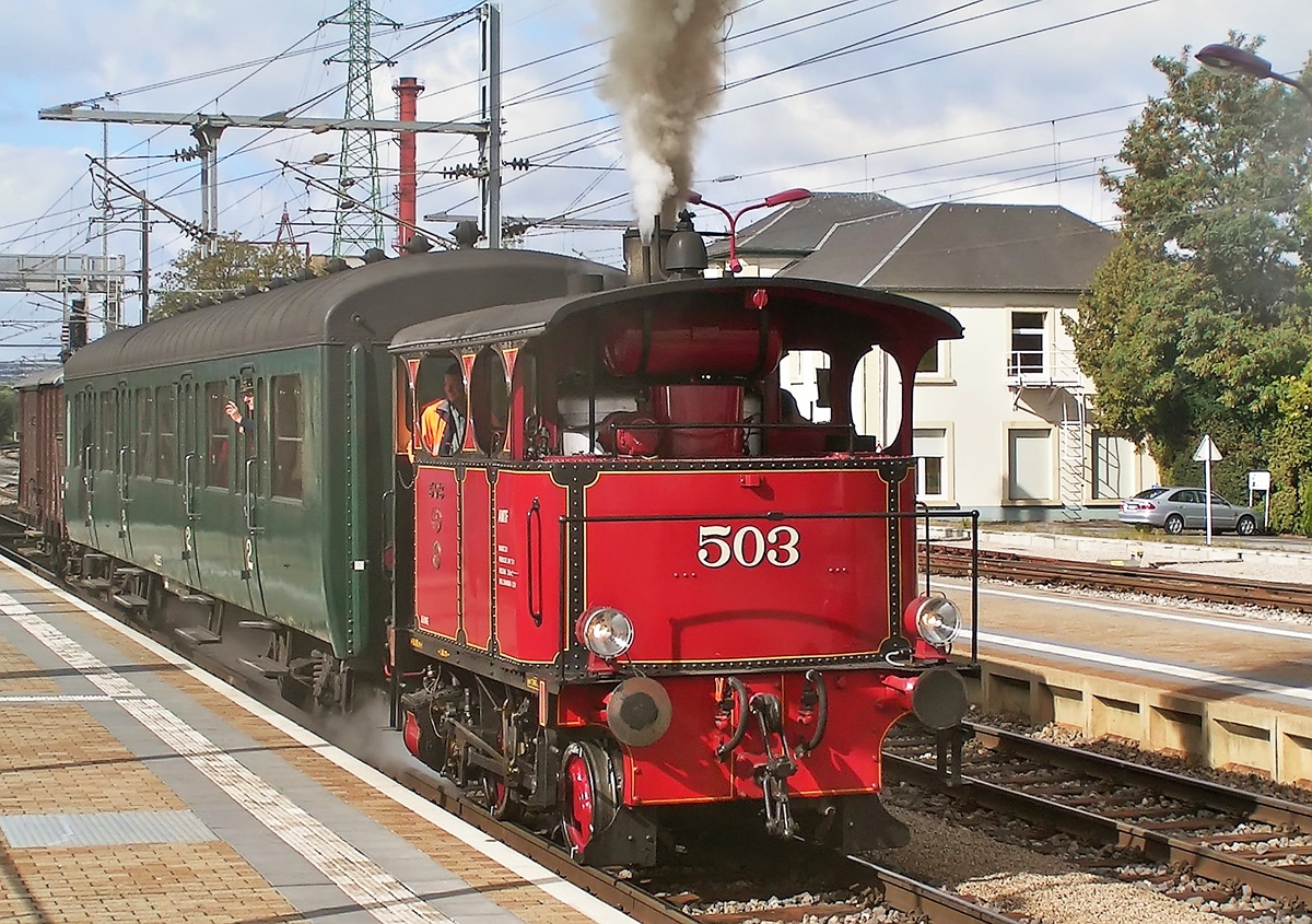 . Nachdem die Stehkesseldampflok Cockerill 503 der Museumsbahn  Train 1900  den ganzen Bahnhof von Rodange in Dampf geh�llt hatte, setzte sie sich in Richtung P�tange in Bewegung. Die Cockerill 503 beteiligte sich am 19.09.2004 am Bahnfest  P�iteng am Damp  in dem sie Pendelfahrten zwischen P�tange und Rodange absolvierte. (Hans)

Die Cockerill 503 tr�gt den sch�nen Namen Jeanne und ist seit 1998 bei der Museumsbahn  Train 1900 .

Diese kleine Zweikuppler-Lok ist ein seltenes Unikum mit ihrem Stehkessel und der Dampfbremse. Gebaut wurde sie in Belgien bei der Fabrik John Cockerill, der ersten Fabrik, die (1835) auf dem europ�ischen Kontinent Dampflokomotiven baute, und die bekannt war f�r ihre Stehkessel-Konstruktionen.

Es wurden f�nf Serien mit einer Gesamtzahl von 900 Lokomotiven diesen Typs gebaut. Diese zierlichen, aber leistungsf�higen Stehkesselloks  waren ideale Werkrangierlokomotiven, welche dank kurzem Achsenstand auch bei sehr engen Kurvenradien bis 15 m Halbmesser und starke Steigungen problemlos eingesetzt werden konnten.

Die Technischen Daten der Cockerill Stehkessellok:

Erbauer: John Cockerill
Baujahr: 1920
Typ: IVR Origine
Dienstgewicht: 	~ 15 Tonnen
L�nge �ber Puffer: ~ 5 000 mm
H�chstgeschwindigkeit: 20 km/h
Leistung: 115 PS
Rostfl�che: 1,0 m�
Triebraddurchmesser: 700 mm (020 / B n2t)
