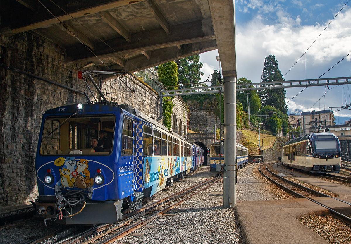 
125 Jahre Glion Rocheres de Naye - Die vom Rochers de Naye eintreffenden Zahnradtriebwagen Bhe 4/8 302  Veytaux  und Bhe 4/8 303  Villeneuve  erreichen am 16.09.2017 Montreux. 
Von der S�ule etwas verdeckt der abgestellte Bhe 4/8 304   La Tour-de-Peilz   und ganz rechts der abgestellte zweiteilige meterspurige MOB ALPINA Triebzug ABe 8/8 9002  Ch�teau-d’�x  (bestehend aus Be 4/4 9203 und ABe 4/4 9302).