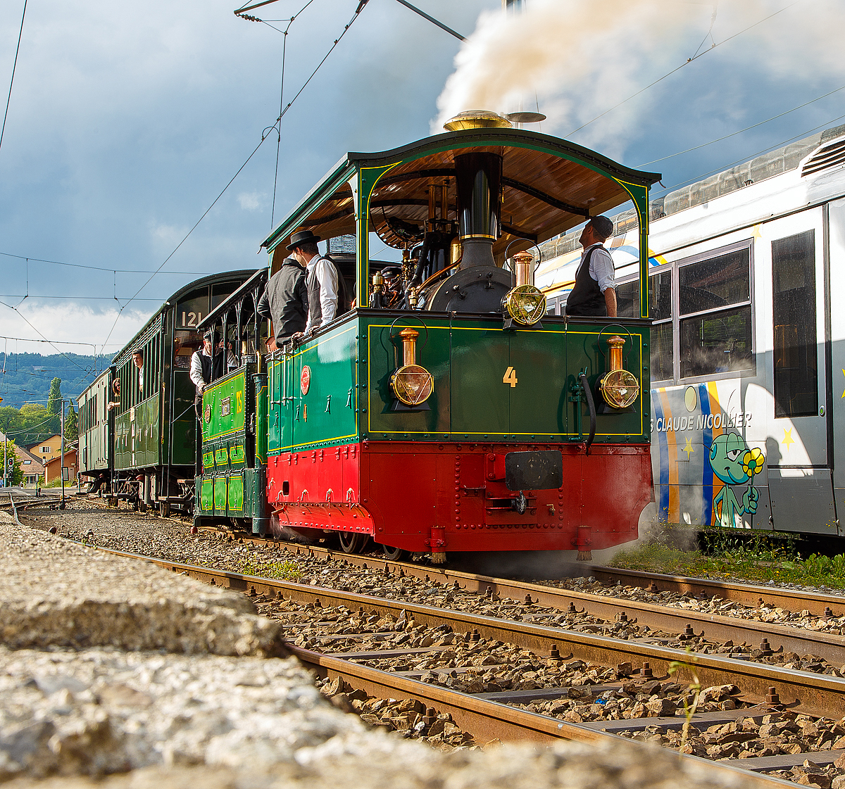 50 Jahre BC - MEGA STEAM FESTIVAL der Museumsbahn Blonay–Chamby - Museumsbahn-Romantik pur:  
In Doppeltraktion fahren die G 2/2 Krauss-Kastendampflok (Tramlok) Nr. 4 der Museumsbahn Blonay–Chamby und die G 3/3 Gastlok (030T) „La Fert�-Bernard“  № 60 mit ihrem Zug am 20.05.2018 vom Bahnhof Blonay wieder hoch nach Chaulin.

Die G 2/2 Krauss-Kastendampflok Nr. 4  wurde 1900 bei Krauss, M�nchen unter der Fabriknummer 4278 f�r die Ferrara Codigoro in Italien gebaut, ab 1907 dann Societ� Anonima delle Ferrovie e Tramvie Padane (FTP) seit 2002 Ferrovie Emilia Romagna (FER). Hier fuhr sie auf der 52 km langen Meterspurstrecke zwischen Ferrara und Codigoro in der Po-Ebene am Rande der Adria. Im Jahr 1932 wurde die Strecke in Normalspur umgebaut, die G 2/2 Nr. 4 wurde dann auf die etwas s�dlichere Strecke Rimini-Novafeltria verlegt die auch zur FTP. Diese 32 km lange Strecke hatte jedoch eine Spurweite von 950 mm, was in Italien relativ �blich war. So musste die G 2/2 Nr. 4 entsprechend um gespurt werde. Die Strecke wurde 1960 eingestellt, das gesamte Rollmaterial stand dann in Rimini herum, wo die Nr. 4 von Mitgliedern der Museumsbahn Blonay–Chamby, in einem schlechten Zustand, entdeckt und 1970 erworben wurde. In �sterreich fand sich auch ein neuer Kessel, der von den Werkst�tten der �sterreichischen Bundesbahnen �BB Knittelfeld angepasst wurde. Nun wieder auf Meterspur drehte G 2/2 Krauss-Kastendampflok Nr. 4, nun mit dem Spitznamen  la Rimini , im Jahr 1981 wieder ihre ersten Runden.

Die G 3/3 Gastlok (030T) „La Fert�-Bernard“  № 60, ex TS Tramways de la Sarthe (eine ehem. meterspurige Dampfstra�enbahnen des Umlandes von  Le Mans) wurde 1898 von ANF Blanc-Misseron unter der Fabriknummer 213 gebaut. Erhalten wird die Lok durch das Mus�e des Tramways � Vapeur et chemins de fer Secondaires fran�ais (Frankreich).
