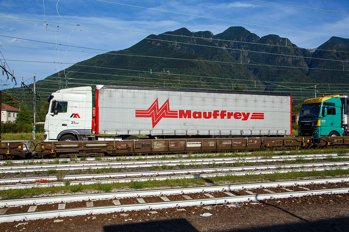 8-achsiger Niederflurwagen �Rollende Landstra�e� der Gattung Saadkms, 84 85 4984 723-6 CH-RALP der RAlpin AG, am 02.08.2019 im Zugverband in Domodossola, in Richtung Simplon fahrend.

Das Fahrzeug ist f�r den Transport von Last- und Sattelz�gen im begleiteten Verkehr, einer Form des kombinierten Ladungsverkehrs, vorgesehen und kommt in alpenquerenden Shuttlerelationen zum Einsatz. Dabei fahren Lastkraftwagen in speziellen Terminals direkt von der Stra�e �ber eine Rampe auf den Wagen, um vom Ausgangsort zum Ziel transportiert zu werden. Der Fahrer zieht sich in einen speziellen Begleitwagen mit Liegeabteilen zur�ck, f�hrt am Zielort weiter und liefert die Ware sicher beim Kunden ab. Diese Form des kombinierten Verkehrs von Schiene und Stra�e – Rollende Landstra�e (ROLA) – gewinnt, nicht zuletzt aufgrund von gesteigertem Verkehrsaufkommen und Umweltbewusstsein, immer mehr an Bedeutung.

Auch in Deutschland (in Nordrhein-Westfalen) denkt man �ber Rola-Z�ge nach, der Grund liegt aber darin, dass eine Talbr�cke der Autobahn A 45 im Raum L�denscheid nicht mehr befahrbar ist. Ein Neubau dauert bekanntlich Jahre, so bleibt auf Jahre hin die Umleitungsstecke �ber Landstra�en (durch L�denscheid) �berlastet.

Die letztentwickelte Version der Wagen erm�glicht eine Zuladung von 44 t sowie mit ihrer nochmals minimierten H�he der Ladefl�che den Transport von Sattelanh�ngern bis 4 m Eckh�he auf der St. Gotthard – Achse.

TECHNISCHE DATEN:
Hersteller: Talbot, Aachen
Spurweite: 1.435 mm
Anzahl der Achsen: 8 (in 2 Drehgestellen)
L�nge �ber Puffer: 19.995 mm (mit Kopfst�ck) / 19.590 mm (ohne Kopfst�ck)
Drehzapfenabstand: 13.700 mm
Achsabstand in den Drehgestellen: 750 / 700 / 750 mm
Laufkreisdurchmesser: 380 (neu) / 355 mm (abgenutzt)
Radsatzlager: TAROL100/175 (Kegelrollenlagereinheiten)
Ladel�nge: 18.600 mm (mit Kopfst�ck) / 19.000 mm (ohne Kopfst�ck)
Eigengewicht: 18.500 kg
Max. Zuladung: (S) 44,0 t ab Streckenklasse A
Zul. Geschwindigkeit: 100 km/h
Kleinster bef. Gleisbogenradius: R 150 m (R 80 m als Einzel Wagen)
Bauart der Bremse: Freno O-GP-A 
Drehgestell-Bauart: gummigefedert BA 690 (Talbot RoLa)