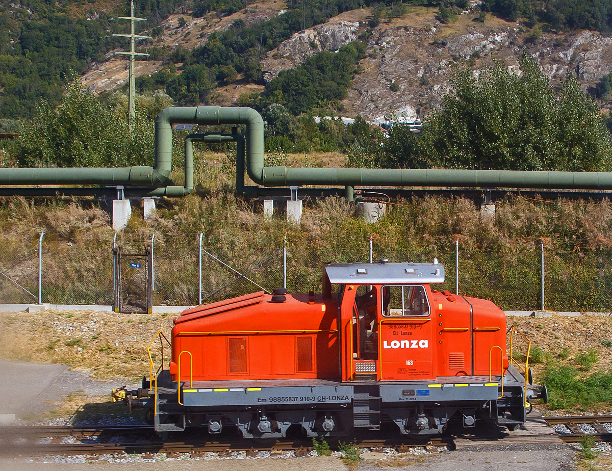 Aus dem Zug heraus, die Em 3/3 163  Rene  (98 85 5837 910-9 CH-LONZA) eine Henschel DHG 500 C der Lonza  AG (Visp), steht am 09.09.2021 in Visp.

Die Henschel  DHG 500 C wurde 1968 von Henschel in Kassel unter Fabriknummer  31239  gebaut und war erst als Mietlok im Einsatz. Im Jahr 1971 verkaufte sie dann Henschel an die Lonza AG in die Schweiz.
2014 wurde die Lok von der LSB Lok Service Balmer AG in Hinwil komplett neu revidiert und remotorisiert.

Die Henschel DHG 500 C ist eine dieselhydraulische Lokomotive, die von den Henschel-Werken gebaut wurde. Sie war vor allem f�r den Einsatz im schweren Werksdienst vorgesehen. Die Lok geh�rt zur ab 1962/63 angebotenen sogenannten vierten Generation der Henschel-Loks, der ersten Generation mit Gelenkwellenantrieb. Die Aufbauten wurden dabei ohne gro�e �nderungen von der vorigen Generation �bernommen.  Zur besseren Bogenl�ufigkeit war die mittlere Achse seitenverschiebbar gelagert. 

Von den Henschel DHG 500 C wurde zwischen 1963 und 1976 insgesamt  62 Exemplaren gebaut. Die Loks gingen vornehmlich an Bergbaugesellschaften und Stahlproduzenten sowie Chemieunternehmen. So erwarb die Rheinelbe Bergbau AG in Gelsenkirchen elf Loks und die Hibernia AG, Zechenbahn- und Hafenbetriebe Ruhr-Mitte in Gladbeck neun Loks vom Typ DHG 500 C. Die meisten Lokomotiven wiesen bei Auslieferung den Henschel-Standardanstrich in Blau mit zwei horizontalen Zierstreifen an den Vorbauten auf. Die durch Zusammenschluss entstandene Ruhrkohle AG hatte zeitweise 31 Lokomotiven dieses Typs im Bestand. 

TECHNISCHE DATEN (nach Umbau):
Spurweite: 	1.435 mm (Normalspur)
Achsformel: C
L�nge �ber Puffer:  9.900 mm
H�he:  4.225 mm
Breite: 3.040 mm
Fester Radstand:  3.700 mm
Kleinster bef. Halbmesser: 	80 m
Dienstgewicht:  60 t
H�chstgeschwindigkeit: 30 km/h / 60 km/h (Schleppfahrt 70 km/h)
Treibraddurchmesser: 	1.000 mm
Motor:  neuer Deutz V6 Motor mit elastischer Vorschaltkupplung. inkl. Partikelfilter (Vollstrombrenner mit aktiver Regeneration), 
der ehemalige Motor war ein Henschel 12V 1416 
Installierte Leistung:  368 kW (500 PS)
Getriebe: 	Voith
Leistungs�bertragung:  hydraulisch (�ber Gelenkwellen)
