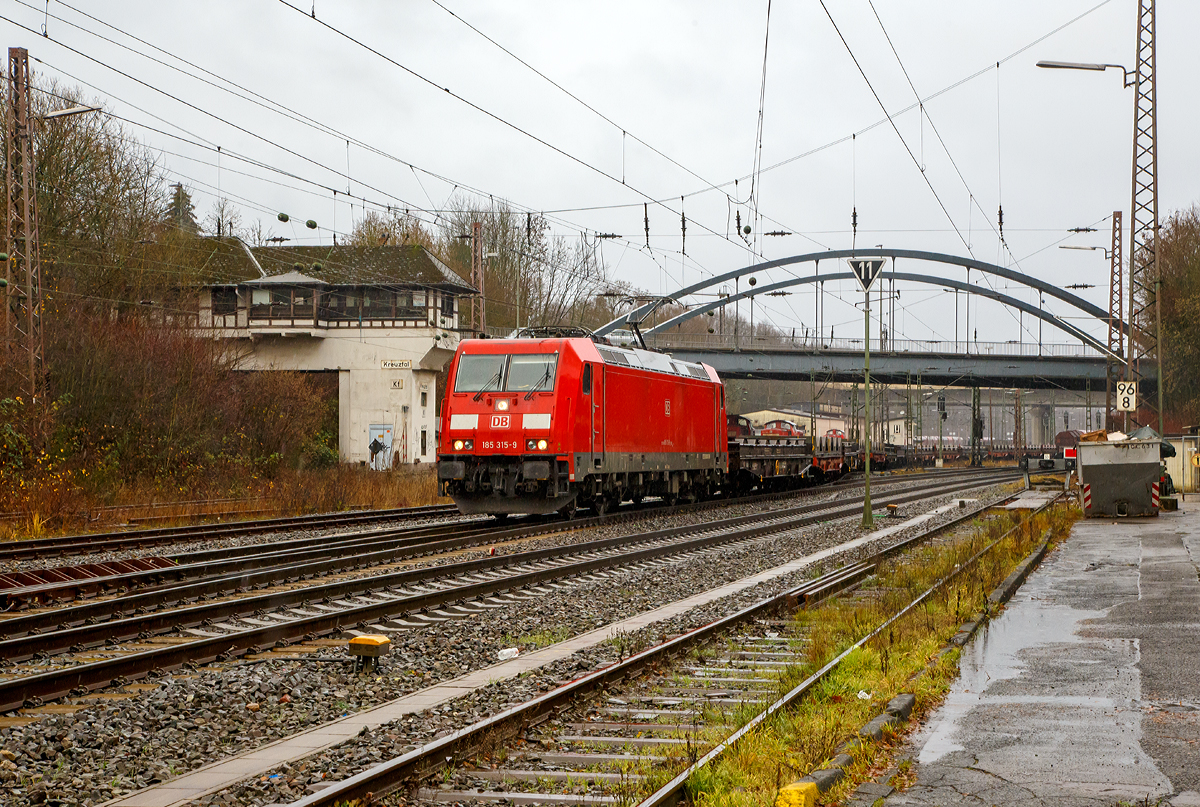 
Bei Regen....
Die DB Cargo 185 315-9 (91 80 6185 315-9 D-DB) verlässt am 08.12.2018 mit einem langen leeren Coilzug den Gbf Kreuztal in Richtung Hagen. 
Für einen beladenen Zug in der Länge und auf dieser Strecke (Ruhr-Sieg-Strecke) hätte die Zugkraft der TRAXX F140 AC2 wohl allein kaum ausgereicht. 

Im Hintergrund das ehemalige Fahrdienstleiter Reiterstellwerk Kreuztal (Kf), es wurde 1923 in Betrieb genommen und steht unter Denkmalschutz.