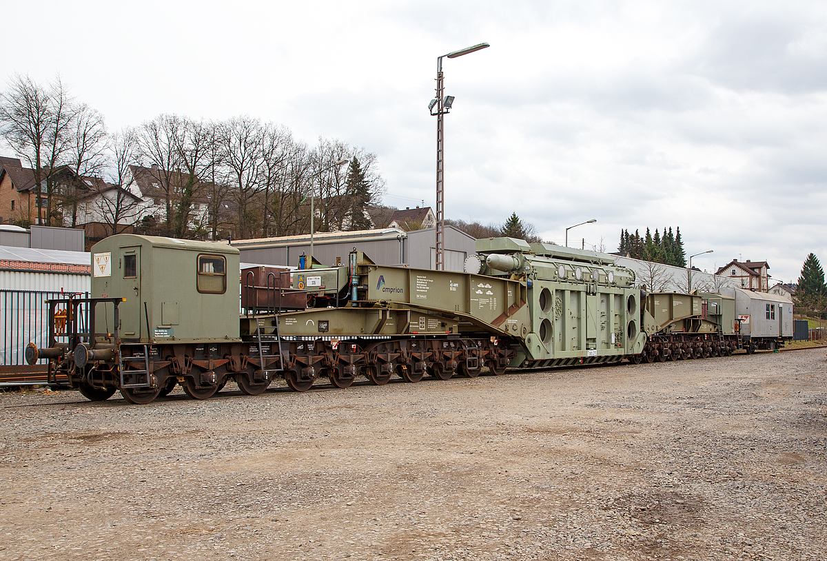 
Der 20-achsiger Tragschnabelwagen der Gattung Uaai 687.9 (84 80 996 0 003-5 D-AMPR) der Amprion GmbH beladen mit einem 150 000 kVA Wandertransformator (Trafo 211) der Trafo-Union (heute Siemens) abgestellt, mit dem Begleitwagen zum Tragschnabelwagen (60 80 092 3 040-0 D-AMPR), am 17.03.2017 in Kreuztal. 

Die Amprion GmbH ist ein deutscher Übertragungsnetzbetreiber für den Strombereich. Das Unternehmen, welches als Teil des RWE-Konzerns entstand, beschäftigt etwa 1100 Mitarbeiter, sein Hauptsitz befindet sich in Dortmund.

Der Tragschnabelwagen wurde 1961 bei MAN unter der Fabriknummer 146523 gebaut. Es wurden 3 Stück der Bauart Uaai 687.9 hergestellt.

TECHNISCHE DATEN:
Spurweite: 1.435 mm (Normalspur)
Anzahl der Achsen: 20 in 4 Drehgestellen á 5 Achsen
Gattung/Bauart: Uaai 687.9
Länge über Puffer: 32.070 mm (Leerfahrt) / 41.140 mm (mit Trafo)
Drehzapfenabstand 1: 15.886 mm (Leerfahrt) / 24.956 mm (mit Trafo)
Drehzapfenabstand 2 (zw. den DG1+2 / DG 3+4): 7.500 mm
Achsabstand in den Drehgestellen: 1.500 mm
Laufraddurchmesser: 1.000 mm
Eigengewicht: 117 t
Maximale Ladegewicht: 250 t
Achsdruck: 5,85 t (Leerfahrt) / 18,35 t (mit Trafo)
Meterlast: 3,65 t/m (Leerfahrt) / 8,92 t/m (mit Trafo)
Höchstgeschwindigkeit: 90 km/h (Leerfahrt) / 40 km/h (Beladen)
Kleinster befahrbarer Gleisbogenhalbmesser: 75 m
Tragende Bauteile gefertigt aus: MSt 52-3
Bauart der Handbremse: bodenbedienbare Handbremse 2 x 45 t