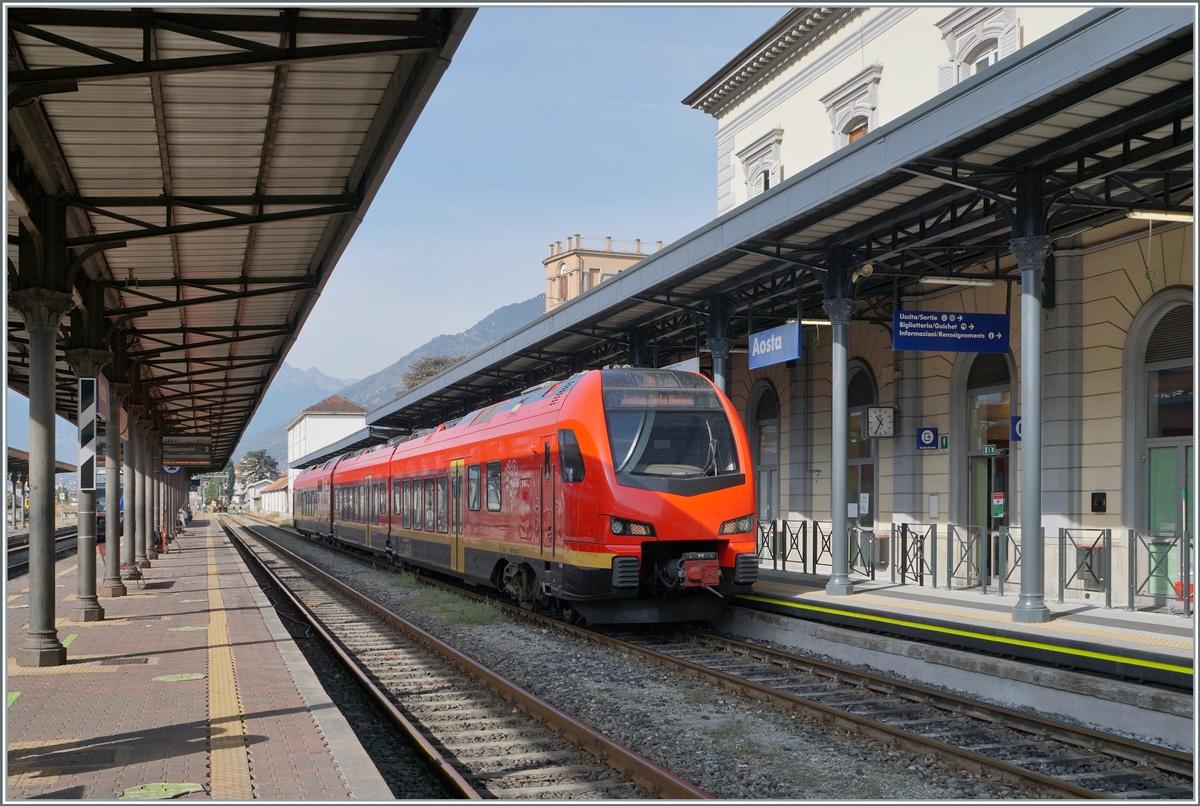 Der bimodale FS Trenitalia BUM BTR 831 003 wartet als Regionale 2722 in Aosta mit dem Ziel Torino Porta Nuova auf die baldige Abfahrt. Der Zug kann mit Dieselmotoren oder elektrisch mit 3000 Volt Gleichstrom betreiben werden, verfügt für die Achsanordnung Bo' 2'2'2' Bo' und die UIC Bezeichnung (des Antriebsmodul) lautet 90 83 1831 012-1 I-TI. 

27. September 2021