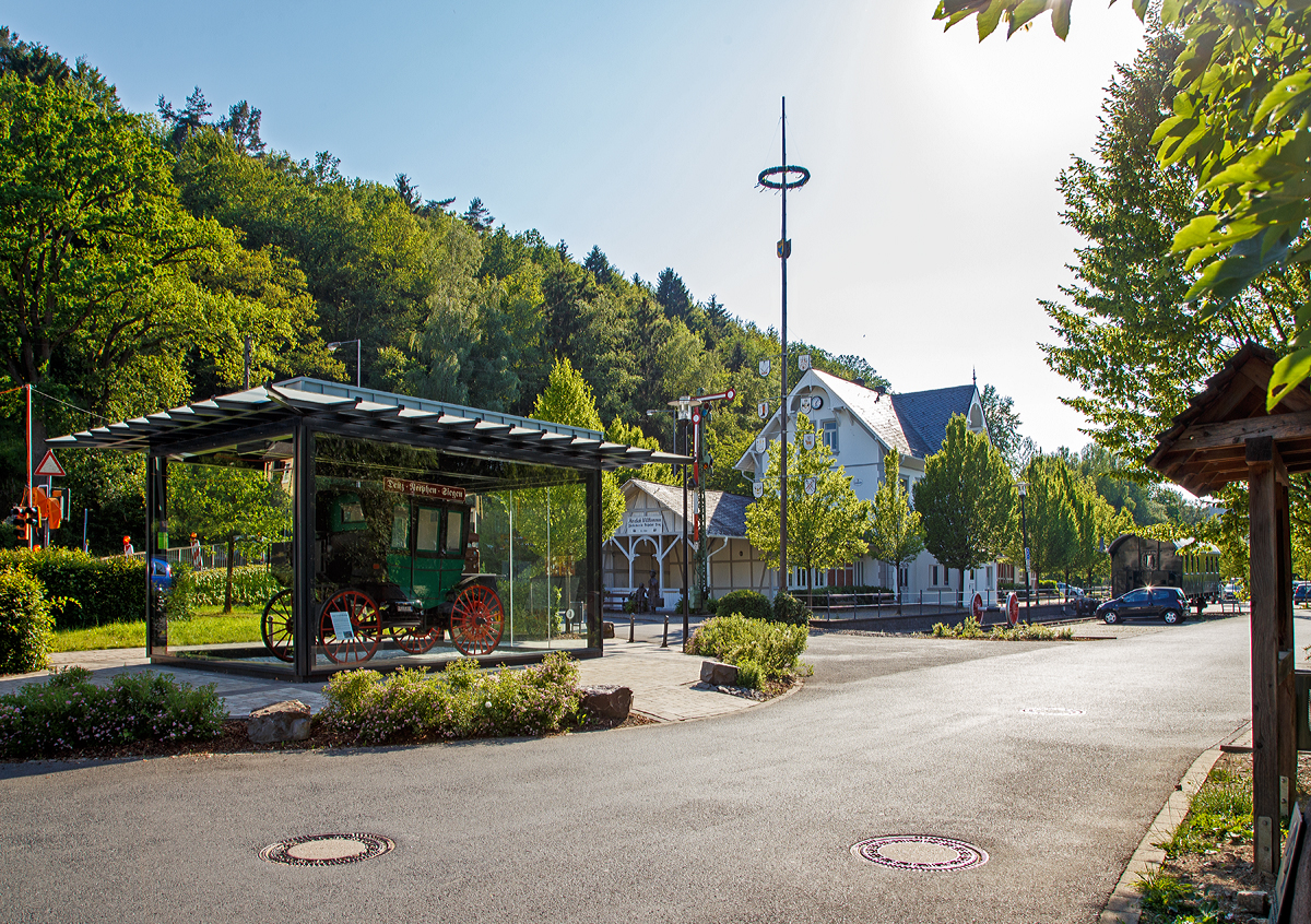 
Der ehemalige Bahnhof  Deuz (heute Netphen-Deuz) der Kleinbahn Weidenau–Deuz GmbH, am 19.06.2019. 
Die GmbH wurde am 4. Juni 1904 gegründet. Das Kapital brachten zu gleichen Teilen das Königreich Preußen, die Provinz Westfalen und der Kreis Siegen auf. Ziel war es, das Amt Netphen im oberen Siegtal mit einer Bahn (Johannlandbahn) zu erschließen.

Der Personen- und Güterverkehr auf dem 11,3 Kilometer langen Teilstück von Weidenau nach Deuz wurde am 1. Dezember 1906 aufgenommen. Die Fortsetzung bis Irmgarteichen-Werthenbach (4,8 km) folgte für Personenzüge am 1. Dezember 1916 und für Güterzüge am 21. Mai 1917.

Über mehrere Jahrzehnte entwickelten sich die Verkehrsleistungen positiv. Auch nach der Einstellung des Personenverkehrs am 25. Mai 1968 nahm der Güterverkehr noch zu.

Am 1. Januar 1970 wurde die Kleinbahngesellschaft Weidenau–Deuz GmbH aufgelöst und ihr Vermögen auf die Siegener Kreisbahn, jetzt: Kreisbahn Siegen-Wittgenstein übertragen, die mehr als 90 Prozent der Gesellschaftsanteile in Besitz hatte und schon seit dem 1. April 1955 Betriebsführerin war.

Erst in den Jahren ab 1990 begann der Rückgang, im Jahr 2004 führ der letzte Güterzug.

Der reguläre Betrieb der Strecke beschränkt sich heute auf den Bereich Weidenau Vorbahnhof bis Dreis-Tiefenbach, dort werden mehrere Industriebetriebe bedient. Mittlerweile endet das Gleis bei KM 2,9 im Werk Bombardier. Dieses stellt Drehgestelle für Eisenbahnen her, früher ganze Güterwaggons.

In Deuz wird noch seit 29. Mai 2004 im Walzenwerk Irle ein Inselbetrieb durchgeführt, dabei sind Werk 1 und 2 noch miteinander verbunden. Für den Werkverkehr ist die von OnRail aufgearbeitet und von der Fa. Irle gekaufte V 60 1175  (zuletzt DB 365 175-9) sowie acht Güterwagen vorhanden. In der Gießerei im Werk II (Gleislänge 320 Meter) werden die Walzenrohlinge abgeholt und zur Bearbeitung nach Werk I (Gleislänge 500 Meter) gebracht. Nach der Bearbeitung werden die Späne wieder zur Gießerei gefahren und die Fertigwaren kommen zum Versandgleis, ebenfalls in Werk II.

Links in dem Pavillon steht ein detailgetreuer Nachbau von erstem benzinbetriebene Omnibus der Welt der 1895 von der Firma Benz & Cie aus Mannheim gebaut und an die die „Netphener Omnibus-Gesellschaft mbH“ geliefert wurde.Technisch gesehen ist der erste Motoromnibus der Welt ein umgebautes Personenwagen-Modell mit einer so genannten Landauer-Karosserie – eine Aufbauart, die damals bei Kutschen weit verbreitet ist. Angetrieben wird er von einem liegenden Einzylinder-Motor im Heck, der 5 PS leistet. Der Antrieb erfolgt über Ketten an die Hinterräder. Der Bus bietet Platz für acht Personen inklusive Fahrer.

Die Idee ist so simpel wie genial: Weil sich seine Automobile zunächst nur schleppend verkaufen, sucht Carl Benz schon kurz nach der Erfindung des Automobils 1886 nach weiteren Einsatzmöglichkeiten für die neue Technik. Um den Kraftwagen größeren Kreisen zugänglich zu machen, erfindet Benz den Omnibus. Geliefert wird das weltweit erste Exemplar an die „Netphener Omnibus-Gesellschaft mbH“ im Siegerland, einer Region im heutigen Nordrhein-Westfalen. Am 18. März 1895 nimmt der erste Motor-Omnibus der Welt den Betrieb auf.

So kann das Netpherland für sich in Anspruch nehmen, die erste Omnibuslinie der Welt besessen zu haben. Der Omnibus war gleichzeitig auch das erste Nutzfahrzeug, das von der Fa. Benz hergestellt wurde.

Der Bus verkehrte zwischen 6.45 Uhr und 20.55 Uhr auf der Strecke Siegen-Netphen-Deuz. Betrieben wurde die Linie von einer Art Aktiengesellschaft. Der erste Bus verkehrte am 18.3.1895. Unlösbare technische Probleme und häufige Reparaturen zwangen die Gesellschaft, den Busverkehr bereits zum 20.12.1895 einzustellen.
