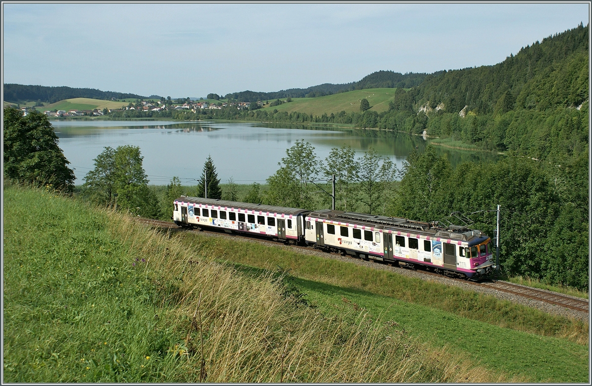 Der ex MThB ABDe 4/4 (538 316-1) mit seinem Bt zeigt sich leider etwas zu üppig mit Werbung beklebt in der sonst so entspannten Juralandschaft des Vallée des Joux bei Le Pont. 
16. Aug. 2009