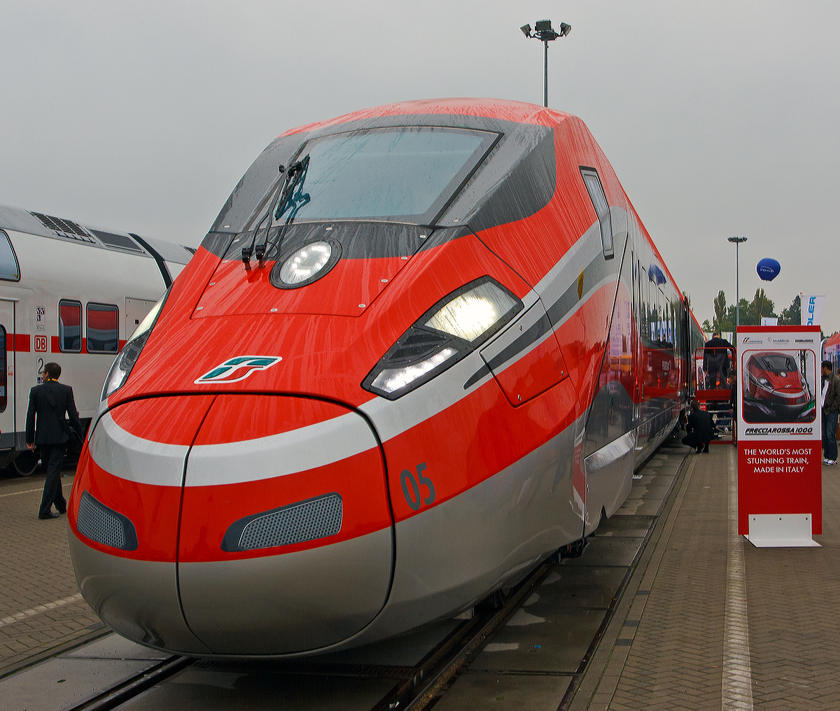 
Der neuste  Rote Pfeil  ETR 1000 (offiziell nun ETR 400), hier am 26.09.2014 pr�sentiert auf der Inno Trans 2014 in Berlin. Man wirbt auch mit dem Slogan „The World's most stunning Train, Made in Italy” (ich w�rde es �bersetzen „Dem weltweit beeindruckenden Zug, Made in Italy“)

ETR 1000, auch Frecciarossa 1000 oder V300 Zefiro, ist eine Baureihe von italienischen Hochgeschwindigkeitsz�gen, die durch ein Konsortium bestehend aus Bombardier Transportation und AnsaldoBreda hergestellt werden. 50 Z�ge sind bestellt. Die italienische Trenitalia, 100-prozentige Tochtergesellschaft der Ferrovie dello Stato Italiane (FS) will auf ihren Schnellstrecken k�nftig mit Tempo 360 km/h fahren.

Im Gegensatz zum ETR 500 ist die Antriebsausr�stung nicht mehr in zwei Triebk�pfen konzentriert, sondern �ber die ganze L�nge des Zuges verteilt. Der Zug basiert auf dem Bombardier Zefiro f�r China und dem AnsaldoBreda V250. Er ist ausgelegt f�r einen Betrieb mit 360 km/h und soll w�hrend Testfahrten 400 km/h erreichen.   Zur Expo 2015 sollen im Juni 2015 die ersten vier der Z�ge in den Betrieb gehen, vorerst mit 300 km/h, sp�ter mit 360 km/h. Dadurch w�rde sich die Reisezeit zwischen Mailand und Rom von 3 Stunden auf 2 Stunden 15 Minuten verk�rzen.

Die acht Wagen bestehenden 202 m langen Triebz�ge sind f�r vier Stromsysteme ausgelegt. Sie k�nnen europaweit verkehren. Ihr Einsatz ist u.a. auch der k�nftigen Hochleistungsstrecke von Italien durch den neuen Brennertunnel (nicht vor 2025) nach Deutschland geplant. Die Roten Pfeile der Generatio1000 bieten in der achtteiligen Konfiguration jeweils 469 Sitzpl�tze sowie Abteile f�r Rollstuhlfahrer.  

Mit 400 Stundenkilometer w�re der ETR 1000 - Der schnellste Zug der Welt - Ein Zeichen an die Konkurrenz.

Technische Daten:
Hersteller:  Bombardier Transportation, AnsaldoBreda
Spurweite: 1.435 mm (Normalspur)
Achsformel:  Bo'Bo'+2'2'+Bo'Bo'+2'2'+2'2'+Bo'Bo'+2'2'+Bo'Bo'
L�nge:  202 m
H�he:  4080 mm
Breite:  2924 mm
Dienstgewicht:  500 t (besetzt)
Radsatzfahrmasse:  17 t
Raddurchmesser: 920 mm (neu) / 850 mm (abgenutzt)
H�chstgeschwindigkeit:  360 km/h (geplant) / 400 km/h (Konstruktiv auf Schnellstrecken mit 25kV-Elektrifizierung)
Dauerleistung:  9.800 kW
Anfahrzugkraft:  370 kN
Beschleunigung:  bis zu 0,7 m/s�
Bremsverz�gerung:  bis zu 1,2 m/s�
Stromsysteme:  15 kV 16,7 Hz AC (Option); 25 kV 50 Hz AC; 
1,5 kV DC und 3 kV= DC
Anzahl der Fahrmotoren:  16
Sitzpl�tze:  469 + 2 Rollstuhlpl�tze

Diese Z�ge haben keine Neigetechnik.
