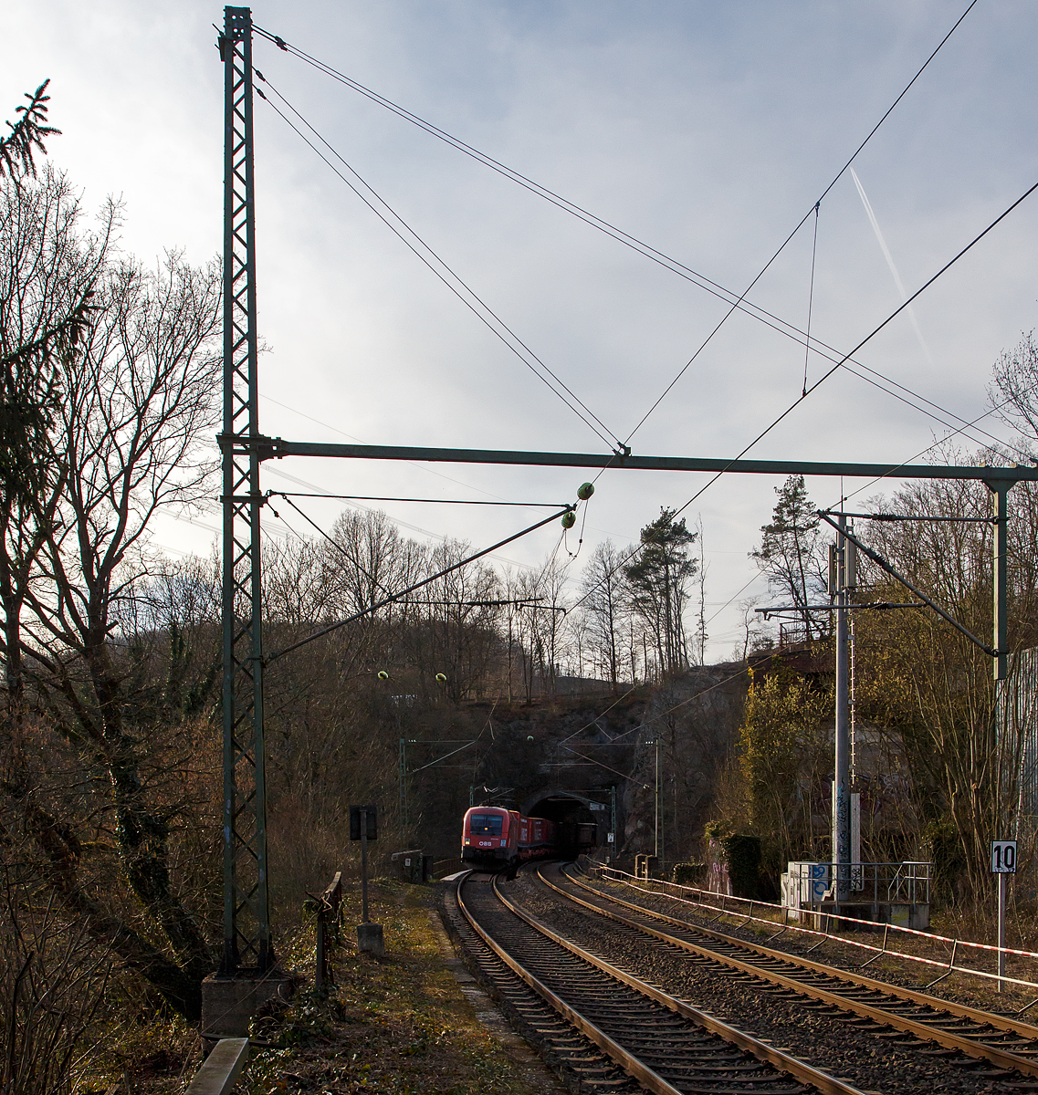 Der ÖBB Taurus 1016 041 (91 81 1016 032-5 A-ÖBB) fährt am 12.03.2022 mit einem  Winner -KLV-Zug bei Scheuerfeld (Sieg) durch den 32 m langen Mühlburg-Tunnel und über nachfolgende Siegbrücke in Richtung Siegen.

Der Taurus wurde 2001 vom Siemens-TS Werk in Linz unter der Fabriknummer 20389 gebaut und an die ÖBB - Österreichische Bundesbahnen geliefert.