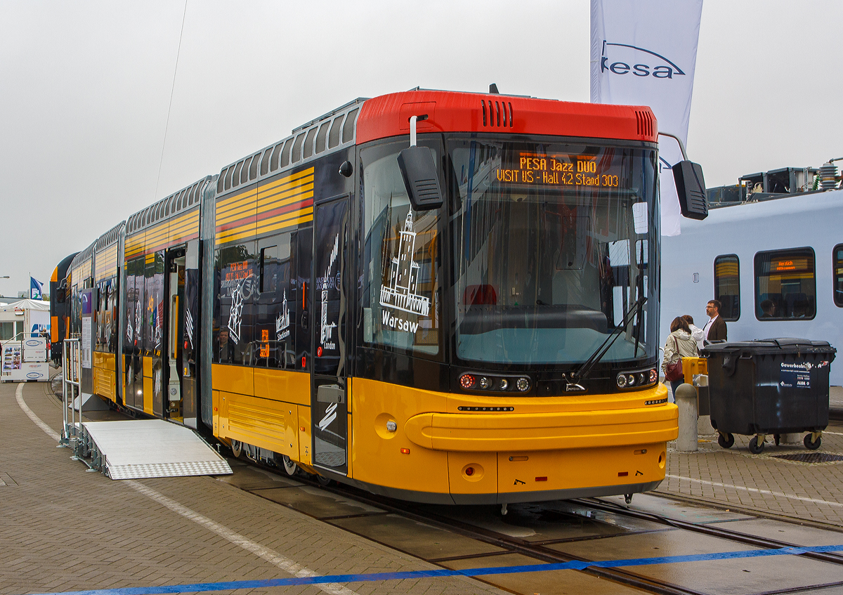 
Der polnische Hersteller PESA (Pojazdy Szynowe Pesa Bydgoszcz SA) pr�sentierte auf der InnoTrans 2014 in Berlin (26.09.2014) den Pesa Jazz Duo, hier in der Farbgebung f�r die Stra�enbahn Warschau (Tramwaje Warszawskie). 

Der Pesa Jazz Duo, ist ein f�nfteiliger, in Niederflurtechnik ausgef�hrter Stra�enbahn-Gelenktriebwagen des Herstellers Pesa aus Bydgoszcz in Polen. Die Stra�enbahn Warschau bestellte 50 Fahrzeuge, die als 128N bezeichnet werden, die Stra�enbahn Danzig bestellte f�nf Fahrzeuge, die als 128NG bezeichnet werden. Der Pesa Jazz Duo ist ein Zweirichtungsfahrzeug, w�hrend der Pesa Jazz des Typs 134N auch ein Einrichtungsfahrzeug ist.

Technik:
Die Fahrmotoren des Jazz Duo treiben jeweils ein einzelnes Rad an, kommen so ohne Radsatzwellen aus und erm�glichen die Fu�bodenh�he von 350 mm, die einen barrierefreien Einstieg gew�hrleisten soll. Ein Gelenktriebwagen hat acht Motoren, zwei der drei Drehgestelle werden angetrieben. Hersteller der Motoren ist das �sterreichische Unternehmen Traktionssysteme Austria.

Auf jeder Fahrzeugseite befinden sich sechs Einstiegst�ren, davon zwei einfl�gelige Schiebet�ren an den Fahrzeugenden und vier doppelfl�gelige Schiebet�ren in den S�nften. Es gibt eine Klimaanlage und ein Fahrgastinformationssystem mit LCD-Monitoren. Die F�hrerst�nde sind vom Fahrgastraum abgetrennt.

Die Warschauer Fahrzeuge besitzen Superkondensatoren, welche die Energie der Nutzbremse zwischenspeichern k�nnen und so eine Energieersparnis von bis zu sieben Prozent erreichen k�nnen. Die Masse der Kondensatoren betr�gt etwa 500 kg, dennoch ist der Jazz Duo leichter als die Vorg�ngerbaureihe PESA 120Na. Die in den Kondensatoren gespeicherte elektrische Energie kann au�erdem genutzt werden, um im Falle eines Stromausfalls wenige Meter ohne Energiezufuhr zur�ckzulegen und so kritische Bereiche wie Stra�enkreuzungen zu r�umen.

TECHNISCHE DATEN:
Spurweite: 1.435 mm (Normalspur)
Achsformel: Bo’0’2’0’Bo’
L�nge: 29.700 mm
H�he:  3.400 mm (bis Dach)
Breite: 2.400 mm
Drehgestellachsstand: 1.850 mm
Dienstgewicht: 	41,5 t
H�chstgeschwindigkeit: 70 km/h
Installierte Leistung:  8 � 60 kW
Motorentyp: TMR 35-18-4
Sitzpl�tze: 	28
Stehpl�tze: 187
Fu�bodenh�he: 	350 mm
Niederfluranteil: 	100 %
