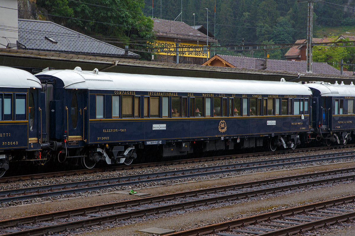 Der VSOE Schlafwagen Nr. 3483 – VSOE VSOE Sleeping-Car / Voiture-Lits / Carrozza-Letti N� 3483 (F- VSOE 61 87 06-70 483-9) im Zugverbund vom Venice Simplon-Orient-Express am 02.08.2019 beim Halt in G�schenen (CH), leider bei Regen.

Der Schlafwagen, ein CIWL Typ Lx wurde 1929, von Metropolitan Cammell Carriage and Wagon Company (MCCW, auch bekannt als Metro-Cammell) in Birmingham (GB) gebaut und als Schlafwagen (WL) vom Typ Lx 16 an die CIWL geliefert die ihn als Nr. 3483 bezeichnete.

Die weitere Geschichte des Schlafwagens war, laut Belmond – VSOE zitiert (aus dem englischen �bersetzt): „Gebaut 1929 in Birmingham. In den 1930er Jahren war er Teil des Le Train Bleu, des Rome Express und des Nord Express. Zu Kriegsbeginn wurde er in Pouanc� abgestellt. Nach dem Krieg diente der Wagen im Simplon-Orient-Express und fuhr von 1973 bis 1977 im Costa Brava Express.“ 

Ende der 1970er Jahre wurde er an die VSOE (Venice Simplon-Orient-Express Ltd.) verkauft. Hier wurde der Wagen �berholt und technisch modernisiert, unter anderem mit Klimaanlagen. Bei den VSOE-Wagen wurde ein Schlafwagenabteil zum Abteil f�r den Schlafwagenschaffner hergerichtet, die Wagen werden seitdem (wieder) als Typ Lx 18 bezeichnet. 

Zwischen 2003 und 2006 wurde die Wagen der VSOE nochmals modernisiert und erhielten unter anderem moderne Drehgestelle von Bombardier sowie neue Klimaanlagen. Durch die neuen Drehgestelle sind die Wagen seitdem f�r 160 km/h zugelassen.

TECHNISCHE DATEN:
Spurweite: 1.435 mm (Normalspur)
Anzahl der Achsen: 4 in zwei Drehgestellen
L�nge �ber Puffer: 23.452 mm
Drehzapfenabstand: 16.000 mm
Achsabstand im Drehgestell: 2.500 mm
Eigengewicht: 54 t
H�chstgeschwindigkeit: 160 km/h (urspr�nglich 130 km/h, sp�ter 140 km/h)
Betten- und Sitzpl�tze: 18 (in 9 Zweibettabteilen), plus Schaffnerabteil
Bremse: Frein MH

