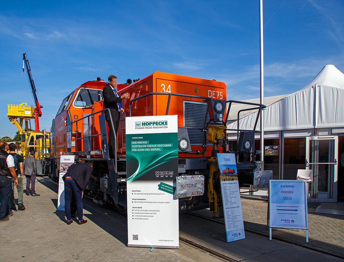Der zur ZAGRO Group geh�rende Hersteller  GMEINDER LOKOMOTIVEN GmbH (Mosbach) pr�sentierte auf der InnoTrans 2018 in Berlin (hier 18.09.2018) seine Rangierlokomotive mit elektrischer Leistungs�bertragung DE75 BB Dual Engine, hier in Form der ArcelorMittal 34, NVR-Nummer 92 80 1075 034-9 D-GL.

Die DE 75 BB Dual Engine wurde 2018 von Gmeinder in Mosbach unter der Fabriknummer 5777 gebaut und hier auf der Messe  InnoTrans 2018  ausgestellt bevor sie dann an die ArcelorMittal Eisenh�ttenstadt Transport GmbH in Eisenh�ttenstadt als Lok 34 ArcelorMittal 1075 034-9 ausgeliefert wurde.

Die DE75 BB ist eine robuste Rangierlokomotive f�r den schweren Rangierdienst. Die elektrische Leistungs�bertragung mit vier unabh�ngig geregelten Fahrmotoren erm�glicht die optimale Ausnutzung der Adh�sion und gleichzeitig die Verwendung verschiedenster Energiequellen. Durch den symmetrischen Aufbau der Lokomotive k�nnen zwei Energiequellen eingebaut werden, zum Beispiel (wie hier) zwei Diesel-Generator-Aggregate (Dual-Engine Lokomotive) oder ein Dieselaggregat und ein Lithium-Ionen-Batteriesatz (Hybridlokomotive). Auch eine Energiezuf�hrung �ber Stromschiene (DC 750 V) oder Fahrdraht ist m�glich. Der symmetrische Aufbau der Lokomotive setzt sich auch in der Leistungselektronik fort. Zwei unabh�ngige Teilsysteme gew�hrleisten h�chste Verf�gbarkeit der Lokomotive.

Die ist zugelassen, Zugfahrten au�erhalb von Bahnh�fen sind jedoch nicht m�glich, da der Erstkunde Arcelor Mittal die Lok ohne Zugsicherung und Zugfunk geordert hat. 

TECHNISCHE DATEN der DE75 BB Dual Engine:
Hersteller:	GMEINDER LOKOMOTIVEN GmbH (Mosbach)
Spurweite:  1.435 mm
Achsformel: Bo‘ Bo‘
L�nge �ber Puffer: 14.080 mm
Drehzapfenabstand: 5.600 mm
Achsabstand im Drehgestell: 2.400 mm
Breite: 3.080 mm
H�he: 4.260 mm
Dienstgewicht: 80 t
Achslast: 20 t
H�chstgeschwindigkeit: 100 km/h
Min. Dauerfahrgeschwindigkeit: kleiner 1,0 km/h
Motorleistung: 2 x 354 kW
Leistung am Rad: 600 kW 
Anfahrzugkraft: 260 kN
Kleinster befahrbarer Gleisbogen: R  60 m
Tankinhalt: 1.900 Liter
Sandvorrat: 500 kg
Fahrzeugbegrenzung:   UIC 505-1
