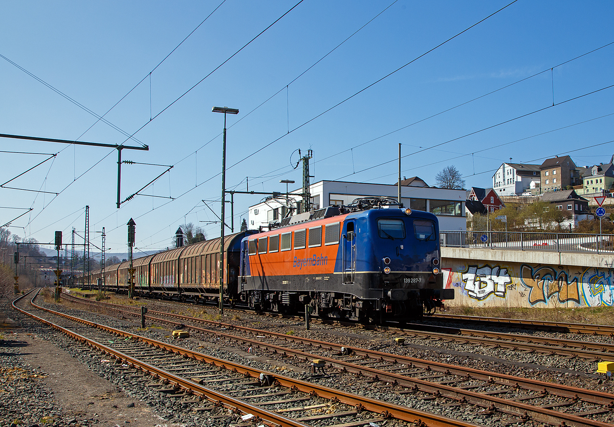 Die 139 287-7 (91 80 6139 287-7 D-BYB) der BayernBahn GmbH fährt am 24.03.2021 mit dem sogenannten  Henkelzug  (Langenfeld/Rhld. nach Gunzenhausen), durch Niederschelden (Sieg) in Richtung Siegen.

Die Lok wurde 1963 von Krauss-Maffei AG in München-Allach unter der Fabriknummer 18956 gebaut, er elektrische Teil ist von den Siemens-Schuckert-Werke (SSW) in Berlin. Als DB E10 287 wurde in Dienst gesetzt, mit der Einführung des EDV-Nummernsystems wurde sie zum 01.01.1968 zur DB 110 287–0. Die Lok ist mit Einholmstromabnehmern ausgerüstet, sie ist die letzte gebaute Kasten 110er. Zur 139er wurde sie erst 1994 nach einem Umbau, der Lokkasten wurde auf Drehgestelle der Baureihe 140 (E40) gesetzt und es folgte die Umzeichnung in DB 139 287-7. Zum Mai 2009 erfolgte die Z-Stellung bei der DB AG.

Zum 1.Oktober 2011 wurde die Lok durch die BayernBahn GmbH erworben und erhielt anschließend eine Untersuchung. Die Neulackierung in kobalt-blau/orange erhielt sie dann 2017.
