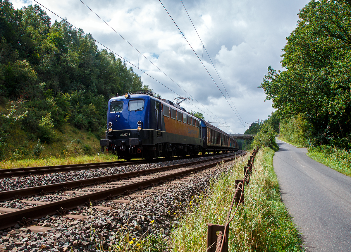 Die 139 287-7 (91 80 6139 287-7 D-BYB) der BayernBahn GmbH fährt am 26.08.2021 mit dem sogenannten  Henkelzug  (Langenfeld/Rhld. nach Gunzenhausen), bei Wissen (Sieg) über die Siegstrecke (KBS 460) in Richtung Siegen.

Die Lok wurde 1963 von Krauss-Maffei AG in München-Allach unter der Fabriknummer 18956 gebaut, er elektrische Teil ist von den Siemens-Schuckert-Werke (SSW) in Berlin. Als DB E10 287 wurde in Dienst gesetzt, mit der Einführung des EDV-Nummernsystems wurde sie zum 01.01.1968 zur DB 110 287–0. Die Lok ist mit Einholmstromabnehmern ausgerüstet, sie ist die letzte gebaute Kasten 110er. Zur 139er wurde sie erst 1994 nach einem Umbau, der Lokkasten wurde auf Drehgestelle der Baureihe 140 (E40) gesetzt und es folgte die Umzeichnung in DB 139 287-7. Zum Mai 2009 erfolgte die Z-Stellung bei der DB AG.

Zum 1.Oktober 2011 wurde die Lok durch die BayernBahn GmbH erworben und erhielt anschließend eine Untersuchung. Die Neulackierung in kobalt-blau/orange erhielt sie dann 2017. 