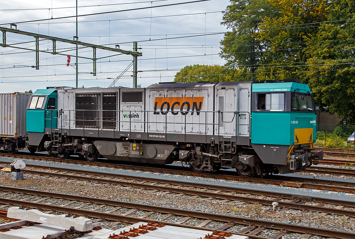 Die an die LOCON Benelux B.V. (Zwolle) vermietete 272 404-5 (92 80 1272 404-5 D-LBL) der Alpha Trains Belgium steht am 03.10.2015 mit einem Güterzug bei Sittard (NL). Bild aus dem Zug heraus. 

Die Vossloh G 2000-3 BB (mit symmetrisches Führerhaus) wurde 2005 von Vossloh in Kiel unter der Fabriknummer 5001605 gebaut. Sie hat die Zulassungen für Deutschland, die Niederlande und Belgien.

Die Lokomotive Vossloh G 2000 BB ist die stärkste dieselhydraulische Lokomotive der Vossloh Locomotives GmbH und wird seit dem Jahr 2000 gebaut. Ihre Achsfolge ist B’B’. Sie hat eine Leistung von bis zu 2.700 kW und erreicht je nach Motorisierung eine maximale Geschwindigkeit von bis zu 140 km/h. Je nach Ausrüstungsvariante bringt sie es auf ein Dienstgewicht von 84 t bis 90 t. Dabei erreicht sie eine Anfahrzugkraft von 283 kN bei 87,3 t. Das Tankvolumen beträgt 5000 l. Insgesamt gibt es 99 Loks der Typen 1–3 und je eine Lok der Typen 4 und 5. 

War das breitere Führerhaus zunächst nur für die italienische Ausführung wegen des dort vorgeschriebenen Beimannes und der dort üblichen Linkssteuerung gedacht, wurde es auch bei der dritten Version für den Verkehr in Deutschland, Niederlande, Belgien und Frankreich beibehalten, allerdings mit Steuerplatz auf der rechten Seite. Bei der ersten Serie befindet sich der Steuerplatz in der Mitte.

Die Lokomotiven haben einen tragenden Rahmen mit angesetzten Frontschilden als Kollisionsschutz. An beiden Seiten gibt es einen Endführerstand, entweder asymmetrisch, mit einem leicht gewendelten Einstieg (Typ 1) oder (wie hier) über die ganze Fahrzeugbreite. Zum Ende ist der Führerraum leicht eingezogen, auch ab Fensterunterkante wird er nach oben etwas schmaler. Der Zugang zum Führerstand erfolgt von hinten über den Umlauf. Der modular aufgebaute Maschinenraum geht nicht über die ganze Breite, so dass auf beiden Seiten Platz für einen Umlauf mit Geländer gibt. Es gibt fünf Module: Elektronik und Batterien, Kühlanlage mit seitlichen Kühlblöcken, Verbrennungsluftfilter (über dem Getriebe), Motor mit Abgasschalldämpfer und die Druckluftanlage. Im Bereich der beiden Kühlertürme sind an der Seite und im Dach große Lüftungsgitter, unterm Dach mit Lüftungsrotoren. Die Lok hält das niedrige Umgrenzungsprofil UIC 505-1 ein. Als Drehgestelle werden zweiachsige Flexicoil-Drehgestelle mit Radsatzlenkern verwendet, wie sie auch in den anderen Typen der „vierten Generation“ von Vossloh verwendet werden. Als Motor kommt in der Regel ein Viertakt-Motor Caterpillar 3616 B-HD mit 2.240 kW zum Einsatz. Aufgrund der hohen Leistung ist ein Einbau eines Turbowendegetriebes nicht möglich, so kommt ein hydraulisches Voith-Getriebe L 620 reU2 mit nachgeschaltetem mechanischen Wendegetriebe zum Einsatz, das nur im Stillstand betätigt werden kann.

TECHNISCHE DATEN:
Achsformel: B'B'
Spurweite: 1.435 mm (Normalspur)
Länge über Puffer: 17.400 mm
Drehzapfenabstand: 9.500 mm
Achsstand im Drehgestell: 2.400 mm
Treibraddurchmesser:  1.000 mm
Höhe: 4.220 mm
Breite: 3.080 mm
Dieselmotor: Caterpillar V-16-Viertakt-Dieselmotor mit Turboaufladung und Ladeluftkühlung vom Typ CAD 3516 B-HD
Motorleistung: 2.240 kW
Motor-Nenndrehzahl:  1800/min
Getriebe: Voith L 620 reU2
Leistungsübertragung: hydraulisch
Anfahrzugkraft:  283 kN
Dienstgewicht: 87,3 t
Höchstgeschwindigkeit: 120 km/h
Kleinster bef. Halbmesser: 80 m
Bremse: KE-GP
Tankinhalt: 5.000 l