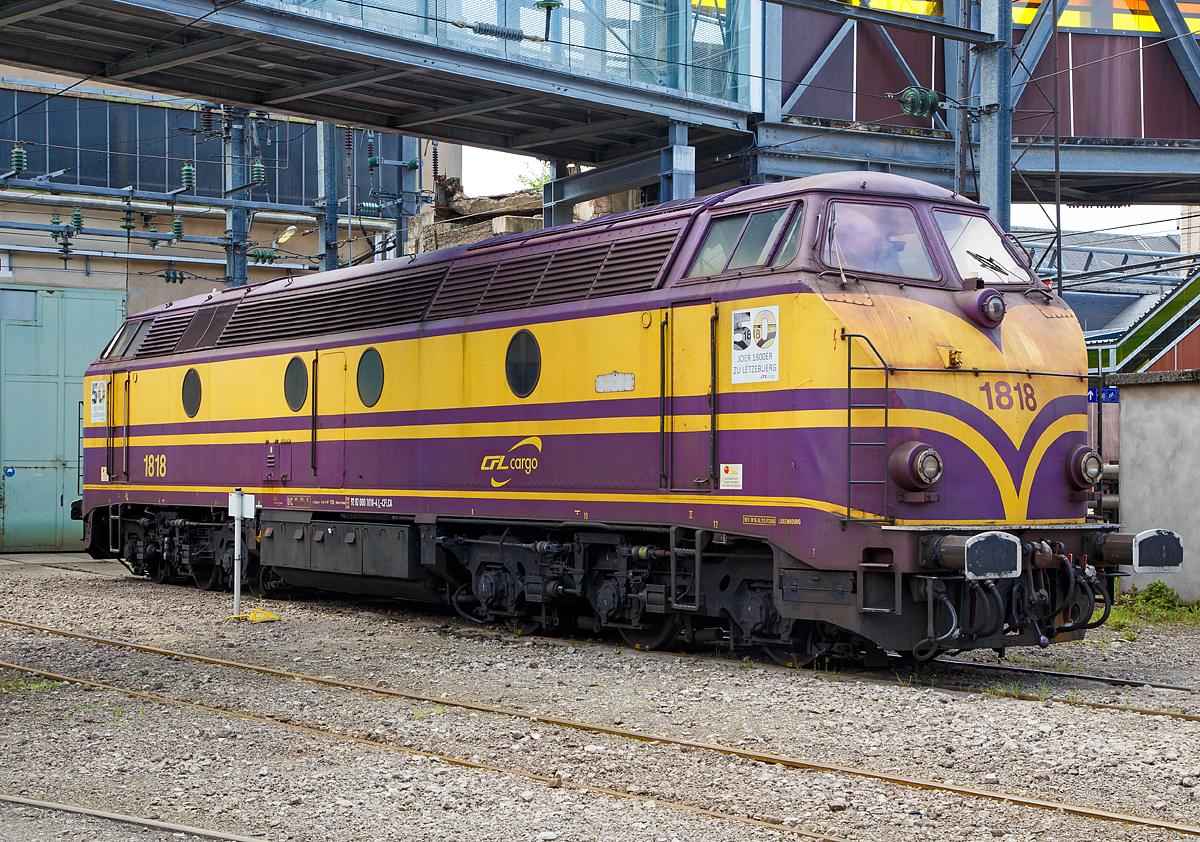 
Die CFL Cargo 1818 (92 82 000 1818-4 L CFLCA) ist am 14.05.2016 beim Bahnhof Luxemburg abgestellt.

Die Lok vom Typ 18 CN 7 wurde 1964 von La Brugeoise et Nivelles (BN) in Belgien gebaut.

Die Luxemburgischen Staatsbahnen CFL (Société Nationale des Chemins de Fer Luxembourgeois) beschafften nach den positiven Erfahrungen mit der Reihe 1600 „Kartoffelkäfer“ (ein Nachbau der Nohab-GM Loks entsprechend der DSB Reihe MY) ein weiterentwickeltes Muster. 1963 und 1964 lieferte  La Brugeoise et Nivelles  (BN) 20 Maschinen als Reihe 1800, die ebenfalls mit dem bewährten EMD 567 motorisiert waren. Äußerlich ließen sich die Loks an den deutlich kantigeren Fronten und den zum Dach hin geneigten, seitlichen Lüftergittern erkennen. 
Die belgischen Staatsbahnen (SNCB) beschafften zuvor (1961 und 62) 42 baugleiche Loks als Reihe 205 (55), allerdings unterscheiden sie sich im elektrischen Teil (Generator und Traktionsmotoren).
Bei dem (General Motors) GM-Dieselmotor handelte es sich um den denselben Typ, der auch in den 1600er Verwendung fand, den V16-Zylinder-Zweitakt-Dieselmotor mit Roots-Lader vom Typ GM 16-567 C. Dieser hat wie allen EMD 567-Motore einen Zylinderdurchmesser von 8 1/2 Zoll (216 mm) und ein Hub von 10 Zoll (254 mm), was zu einem Hubraum von 567 Kubikzoll pro Zylinder, entsprechend 9.292 cm³, führte. Aus diesem Wert leitet sich die Bezeichnung der Baureihe ab. 
Die Drehzahl des Dieselmotors konnte auf 835 U/min gesteigert werden und somit ergab sich eine Leistungssteigerung um 200 PS.

Die Idee, einen 2-Takt-Diesel zu verwenden war theoretisch gut, denn ein 2-Takter erbringt (rechnerisch !) bei gleichem Hubraum die doppelte Leistung eines 4-Takt-Motors, hat also große Gewichtsvorteile und braucht weniger Platz. - In der Praxis wird das jedoch relativ. Bauteile müssen stärker dimensioniert werden, die großen Gebläse (meist Rootsgebläse) und deren Antrieb sind schwer und brauchen einigen Platz. Zudem nutzt der 2-Takt-Motor den Kraftstoff schlechter aus, er  säuft . 

Außerdem ist ein 2-Takt-Diesel sehr laut, fast kreischend, daher auch der typische Sound dieser Lokomotiven.

Technische Daten der CFL 1800:
Hersteller:  BN (La Brugeoise et Nivelles)
Baujahre:  1963-64
Achsfolge:  Co' Co'
Spurweite: 1.435 mm (Normalspur)
Länge über Puffer : 19.550 mm
Höhe:  4.250 mm
Breite:  2.900 mm
Drehzapfenabstand:  10.480 mm
Drehgestellachsabstand:  4.000 mm (2 x 2.000mm)
Treibraddurchmesser:  1.010 mm
Motor:  GM type V16-567C, (Zweitakt-Dieselmotor)
Hubraum: 148,67 Liter
Leistung:  1.360 kW (1.850 PS) bei 835 U/min
Kraftübertragung:  dieselelektrisch (Dieselmotor auf Generator, dieser liefert dann die elektrische Energie für die 6 Fahrmotoren)
Anfahrzugkraft:  272 kN
Höchstgeschwindigkeit: 120 km/h
Dienstgewicht: 110,0 t (mit Heizung 114,0 t)
Tankinhalt:  4.000 l
Kupplungstyp:  Schraubenkupplung