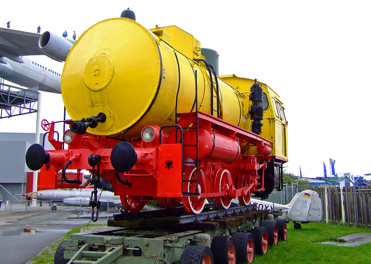Die ehemalige Dampfspeicherlok der VEB Braunkohlenwerk �Erich Weinert�, Deuben, eine LKM vom TypFLC, am 02.10.2010 im Technik Museum Speyer.

Die Lok wurde 1957 bei VEB Lokomotivbau Karl Marx Babelsberg (LKM) unter der Fabriknummer 146629 gebaut und an das VEB Elektrochemisches Kombinat Bitterfeld als Lok Nr. 9 geliefert.

Die bei weitem erfolgreichste Dampfspeicherlok aus DDR-Produktion war die  Feuerlose C  von LKM. Zwischen 1953 und 1961 wurden zun�chst 158 Maschinen geliefert. Da die DDR wegen stets knapper Devisen sehr stark auf die ausreichend vorhandene heimische Braunkohle setzte und diese in fast alle Industriebetrieben in Kesselh�usern verheizt wurde, so dass Prozessdampf vorhanden war, war die Dampfspeicherlok f�r Industriebahnen eine sehr wirtschaftliche Alternative zum Dieselbetrieb. Daher folgten in den Jahren 1969/70 nochmals 40 dieser Maschinen von LKM. Und als damals gegen Anfang der achtziger Jahre nach der zweiten �lkrise der Bedarf an Dampfspeicherloks immer noch nicht gedeckt war, LKM aber 1976 den Lokbau eingestellt hatte, lieferte das RAW Meiningen 1983 bis 1988 nach den alten Pl�nen nochmals 200 Maschinen der  Feuerlosen C  an DDR-Betriebe sowie zwei Loks f�r den Export an die CSSR aus.

Eine Dampfspeicherlokomotive oder feuerlose Lokomotive ist eine spezielle Bauform einer Dampflokomotive, die ihre Antriebsenergie aus �berhitztem Wasser bezieht. Bevor die Dampfspeicherlokomotive betriebsbereit ist, muss das Wasser im Kessel der Lokomotive aus einem externen Dampfkessel erhitzt werden.

Eine Dampfspeicherlokomotive kann in explosionsgef�hrdeten Umgebungen, wie z. B. in der chemischen Industrie, in Munitionsfabriken oder im Bergbau, eingesetzt werden, da bei ihr keine Verbrennung stattfindet. Anh�ngelasten von �ber 2.000 t k�nnen bewegt werden. Nach sechs bis acht Stunden m�ssen sie wieder bef�llt werden. Auch heute noch werden Dampfspeicherlokomotiven in Industriebetrieben eingesetzt, die selbst erhebliche Prozessw�rmemengen erzeugen, etwa die Papier-, die Zucker- und die Eisenindustrie.

TECHNISCHE DATEN:
Spurweite:  1.435 mm
Achsfolge: B
L�nge �ber Puffer: 9.600 mm
H�he: 4.180 mm
Achsstand: 3.600 mm (2x1800 mm) 
Raddurchmesser: 1.050 mm
Zylinderdurchmesser: 660 mm
Kolbenhub: 500 mm
Dampfdruck: 20 bar
Wasserinhalt des Kessels:    17,8 m�
Dampfinhalt des Kessels:      3,2 m�
Gesamtinhalt des Kessels:  21,0 m�
Leergewicht: 33 t
Dienstgewicht: 48 t
Gr��te Zugkraft:  9.600 kg
Zugkraft bei 2 bar: 1.660 kg
kleinster Kr�mmungsradius:    80 m
