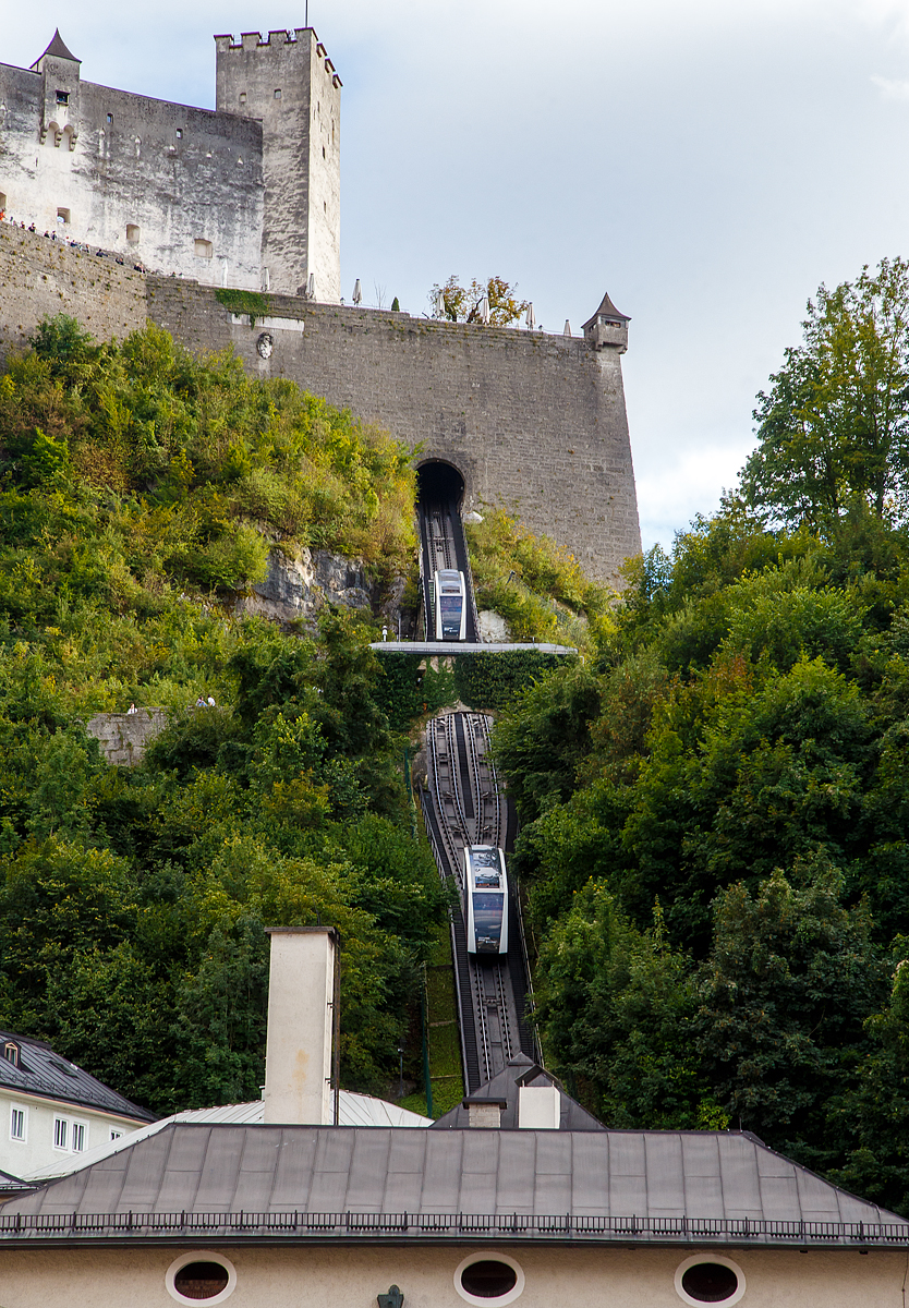 Die FestungsBahn Salzburg am 10.09.2002.

Die FestungsBahn Salzburg ist eine Standseilbahn in der Stadt Salzburg, die zur Festung Hohensalzburg hinaufführt. Die Festung ist eine der größten bestehenden Burganlagen Europas aus dem 11. Jahrhundert. Unter dem Markennamen FestungsBahn wird die Bahn seit 2000 von der Salzburg AG (zuvor SLB) betrieben. Um Jahrhunderte älter ist aber von Nonnberg auf die Festung führend der Reißzug, die älteste bis heute betriebene Materialseilbahn weltweit.

Die Festung Hohensalzburg ist eine der größten bestehenden Burganlagen Europas aus dem 11. Jahrhundert. Die FestungsBahn ist Österreichs älteste, in Betrieb befindliche Standseilbahn. Seit 1892 bringt sie Besucher schnell und sicher auf die Festung. Schon während der Fahrt kann man einen atemberaubenden Blick auf die Stadt Salzburg werfen und oben angekommen lädt das Panorama über Salzburg zum Träumen ein.

Die FestungsBahn ist Österreichs älteste, in Betrieb befindliche Standseilbahn. Sie bringt seit 1892 Besucher schnell und sicher auf die Festung Hohensalzburg. Bis 1959 wurde die FestungsBahn als „Tröpferlbahn“ mit Wasser aus dem Almkanal betrieben, heute ist die Standseilbahn elektrisch unterwegs. In weniger als einer Minute sind die Wagen mit 55 Personen auf der Festung Hohensalzburg. Schon während der Fahrt kann man einen atemberaubenden Blick auf die Stadt Salzburg werfen und oben angekommen lädt der Blick über die Dächer der Stadt zum Staunen ein.  

Elektrische Bahn:
Die Wasserbahn wurde samt Strecke abgetragen und eine neue Gleisanlage mit zwei Wagen installiert. Im April 1960 ging die elektrisch angetriebene Bahn in Betrieb. Die Fahrgeschwindigkeit verdoppelte sich (1,0 m/s auf 2,4 m/s), die neuen Wagen boten Platz für 36 Fahrgäste. Eine Fahrt von der Talstation zur Festung dauerte somit nur noch 80 Sekunden, weniger als die Hälfte der „offiziellen“ Fahrzeit der früheren Wasserbahn.  

Umbau 1991:
40 Millionen Fahrgäste in 31 Jahren machten eine Generalmodernisierung nötig. Wurde zuerst noch an eine kleine Lösung mit Austausch der Wagenkästen gedacht, so entschloss man sich per 1.9.1989 zur Erneuerung des Antriebes und der Wagen als wirtschaftlichste Lösung. Im November 1991 begannen in der Bergstation die Umbaumaßnahmen. Mit dem Neubau wurde die Fahrgeschwindigkeit auf 5 m/s, das Fassungsvermögen auf 48 Personen erhöht. Um dem Fahrgast einen schönen Ausblick auf die Stadt zu ermöglichen, wurden die neuen Wagen mit der damals größtmöglicher Verglasung, speziell auch im Dachbereich, ausgeführt.

Modernisierung 2011:
Nach knapp 19 Jahren kam das Ende der dritten Festungsbahngeneration. Von Januar bis April 2011 wurde die FestungsBahn modernisiert. Die Modernisierung der FestungsBahn wurde der Siemens-Division Industry Solutions Siemens als Generalunternehmer übertragen. Die Firma Carvatech war für den Kabinenaufbau verantwortlich und die Doppelmayr Cable Car GmbH für das Fahrwerk und die mechanischen Komponenten. Rund 4 Millionen Euro wurden in zwei neue Fahrzeuge und die Erneuerung der elektrotechnischen Ausrüstung investiert. Die Wagen werden auf Berg- und Talfahrt von dem jeweils bergseitigen Führerstand aus gesteuert. Die großen Panoramafenster bieten einen optimalen Ausblick auf die Altstadt. Stündlich können bis zu 1.850 Fahrgäste befördert werden.

TECHNISCHE DATEN:
Antrieb: frequenzgeregelter Drehstrommotor (400 V)
Antriebsleistung: 225 kW
Wagenkapazität: 55 Pers. (54 + 1 Wagenbegleiter, bergseitig) auf 3+1 Ebenen
Geschwindigkeit: 5 m/sec.(maximal 5,5)
Spurweite: 1.040 mm
Schräge Länge: 198,5 m 
Höhenunterschied: 102 m
Größte Steigung: 62 % 
Seildurchmesser: 25 mm
Fahrzeit: 48 sec. (ohne Halt auf halber Strecke)
Transportkapazität : 1.850 Pers./h 
Gewicht eines Wagens: 4.125 kg
Wagenlänge: 9.300 mm
