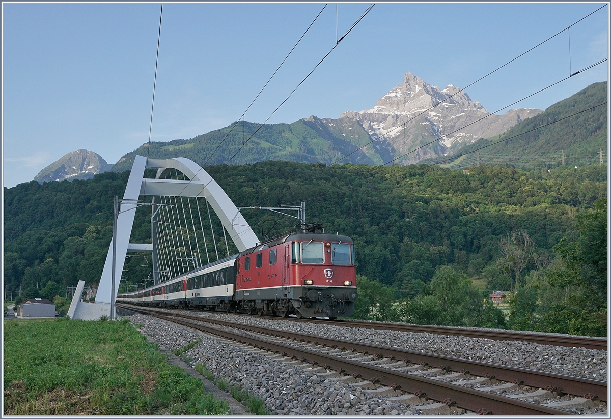 Die HVZ IR 90 vom Wallis nach Lausanne verkehren grundsätzlich im Gegenlicht; da die Züge meist von Re 4/4 II gezogen werden, sind sie trotzdem ein begehrtes Fotomotiv. Das Bild zeigt die Re 4/4 II 11158 mit dem IR 90 1906 von Sion nach Genève Aéroport beim Überqueren der Rhone Brücke kurz vor Bex im noch schattigen Rhone Tal. 25. Juni 2019