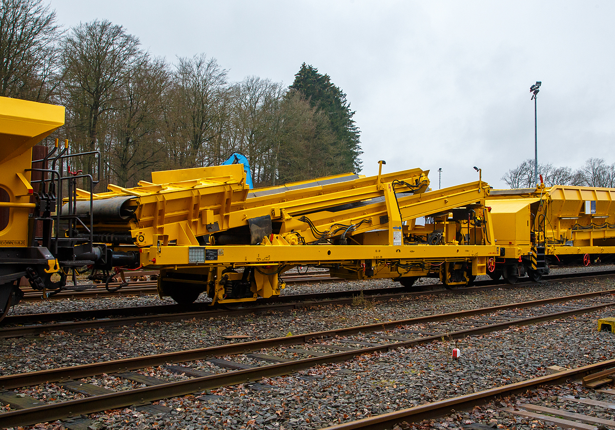 Die Plasser & Theurer Beladestation BLS 2000 (BLS 40 – 2000) der HERING Bahnbau (Burbach) Schweres Nebenfahrzeug Nr. D-HGUI 99 80 9552 123-8, ex 97 19 26 502 57-8 ist am 20.12.2020 auf dem Betriebshof der Westerwaldbahn (WEBA) auf der Bindweide bei Steinebach/Sieg abgestellt.

Die Beladestation wurde 1993 von Plasser & Theurer unter der Fabriknummer 2161 gebaut.

Die BLS 2000 ist ein zweiachsiges, gleisfahrbares Gerät. Die BLS 2000 kann unter spannungsführenden Fahrleitungen eingesetzt werden. Sie kann mit MFS 38, 40, 100, BSW 2000 und 6000 gekoppelt werden. Der Boden des Aufnahmebandes und des Übergabebandes ist als steuerbares Band mit einer Förderbreite von 1.920 mm ausgebildet. An der Baustelle angekommen, ist eine Aufrüstzeit von ca. 3 Minuten nötig. Der Aufnahmetrichter wird auf eine Höhe von max. 1,15 m über SOK abgesenkt und das Übergabeband wird ausgefahren. Hiernach können die Schüttgüter (alter Gleisschotter, Planum etc.) mittels Laderaupe, Radlader oder Bagger über die BLS in die MFS oder BSW verladen werden. Die Förderbänder werden hydraulisch angetrieben. Der Antrieb des Hydraulikaggregates erfolgt durch einen luftgekühlten Deutz Dieselmotor vom Typ F5L912 mit einer Leistung von 64 kW.

TECHNISCHE DATEN:
Achsanzahl: 2
Eigengewicht: 22.600 kg
Länge über Puffer: 12.900 mm
Achsabstand: 8.000 mm
Laufraddurchmesser: 730 mm (neu)
Höchstgeschwindigkeit: 100 km
Kleinster befahrbarer Gleisbogen: R 120 m
Bremse: KE-GP
Handbremse: Ja