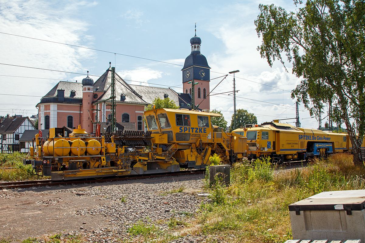 
Die Plasser & Theurer Schotterverteil- und Planiermaschine SSP 2000 der SPITZKE SE, Schweres Nebenfahrzeug Nr. D-SPAG 99 80 9125 007-1, abgestellt am 21.07.2018 in Wissen (Sieg). Dahinter die Plasser & Theurer Dreischwellenstopfmaschine 09-3X Dynamic  der SPITZKE SE, Schweres Nebenfahrzeug Nr. D-SPAG 99 80 9121 006-7.

Die Schnellschotterplaniermaschine SSP 2000 stellt den erforderlichen Regelbettungsquerschnitt in Gleisen und Weichen her. Die Maschine verfüllt, planiert und kehrt das Gleis. Sie verfügt über Besenwellen für alle Oberbauformen.

Funktionsmerkmale:
- Automatische Ausschwenkbegrenzungen der Flankenpflüge verhindern ein Überschreiten des Regellichtraumprofils
- Besenwellenschnellwechselvorrichtung
-  Zwei durchgehende Achsen als Triebachsen
- Durch Schraubenfedern und Stoßdämpfer wird eine ausreichende Absorption von Schwingungen und Stößen und eine große Laufruhe des Fahrzeuges erreicht
- Geschlossene schallisolierte Großraum-, Fahr- und Arbeitskabine am hinteren Teil der Maschine
-  Zwei waagerecht und senkrecht verstellbare Flankenpflüge im vorderen Teil der Maschine
- Mit Planierpflugeinrichtung für schwerste Schotterarbeiten – bestehend aus zwei voneinander unabhängig absenkbaren in Gleisrichtung laufenden Pflughälften
- Kehranlage inklusive einer Kehrbürste und einem Querförderband zur Verfüllung der Zwischenfächer bzw. Ableitung des überflüssigen Schotters auf das Querförderband
- Drehzahl des Bürstenantriebes kann bis max. 350 U/min stufenlos verstellt werden
- Schotterentfernung zwischen Schiene und Kleineisen durch zwei Kleineisenbürsten hinter der Vorderachse
- Ausgerüstet mit Sifa und Indusi


TECHNISCHE DATEN der SSP 2000:
Spurweite: 1.435 mm
Achsformel: A´A´
Länge über Puffer: 17.000 mm
Achsabstand: 10.000 mm
Eigengewicht: 40,3 t
Anhängelast: 60 t
Leistung: 400 kW
Höchstgeschwindigkeit: 100 km/h (Eigenfahrt und geschleppt)
Zugelassen zur Mitfahrt:  4 Personen
Kleinster befahrbarer Kurvenradius:  R 90 m (Arbeitsradius  120 m)     
Zugelassen für Streckenklasse: C2 oder  höher
Bremse: KE-GP mZ
Bremsgewichte: G = 26 t / P = 26 t
Tankvolumen: 2x 1.000l Diesel
Wasservorrat: 1.000 l (für Sprühnebel bei Staubanfall)

Besonderheiten: 5-fach verstellbarer Mittelpflug, Ausschwenkbegrenzung für Pflüge auf mehrgleisigen Strecken

Leistungsparameter
Arbeitsleistung bei Durcharbeitung des Gleises: max. 1.600 m/h
Arbeitsleistung bei Umbau des Gleises: max. 1.200 m/h
Arbeiten in Überhöhung: max. 180 m

Quelle: http://www.technikpark.com (SPITZKE SE), sowie Anschreibungen am Fahrzeug.