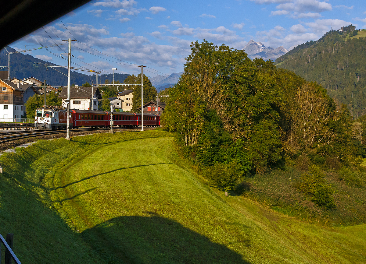 Die RhB Ge 4/4 II 633 „Zuoz“ steht am 07.09.2021im Bahnhof  Castrisch mit dem RE 1720 von Disentis/Mustér nach Chur und muss den Gegenzug, unseren von der RhB Ge 4/4 II 632 „Zizers“ gezogenen RE 1721nach Disentis/Mustér  abwarten. 

Ich fotografiere hier aus dem direkt hinter der Lok hängenden Heiz- und Gepäckwagen (DS 4221), so kann man den Schatten der RhB Ge 4/4 II 632 unten in der Wiese erkennen.
