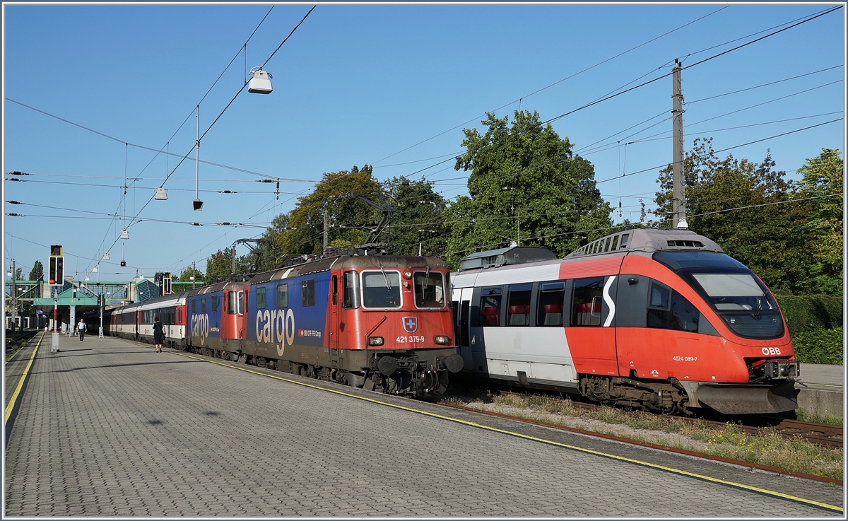 Die SBB Re 421 379-9 und eine weitere mit ihrem EC von Zürich nach München beim Halt in Bregenz. Recht im Bild steht der ÖBB ET 4024 098-7. 

16. Sept. 2019