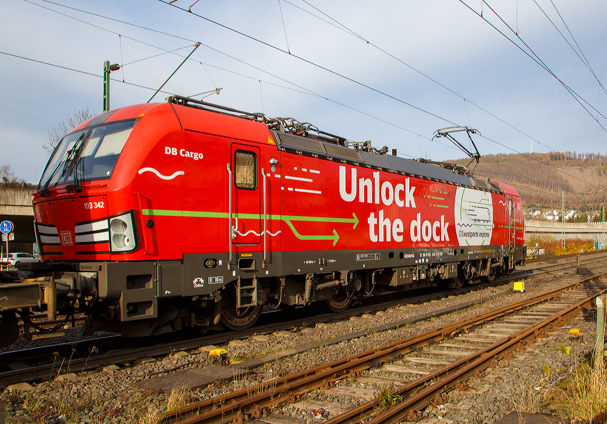 Die Siemens Vectron MS 193 342-3 „Unlock the Dock“ (91 80 6193 343-3 D-DB) der DB Cargo AG fährt am 10.11.2021 mit einem „HUPAC-Zug“ (KLV-Zug) durch Niederschelden in Richtung Siegen.

Die Vectron MS wurde 2018 von Siemens in München unter der Fabriknummer 22422 gebaut und an die DB Cargo geliefert. Diese Vectron Lokomotive ist als MS – Lokomotive (Multisystem-Variante) mit 6.400 kW konzipiert und zugelassen für Deutschland, Österreich, Schweiz, Italien, Belgien und Niederlande, sie hat eine Höchstgeschwindigkeit von 200 km/h. So ist es möglich ohne Lokwechsel vom Mittelmeer die Nordseehäfen Rotterdam oder Hamburg an zu fahren.

Die Vectron MS hat folgende Leistungen:
Unter 15kV, 16,7Hz und 25kV, 50Hz Wechselstrom mit 6.400kW;
unter 3kV Gleichstrom mit 6.000kW sowie
unter 1,5kV Gleichstrom 3.500kW

Auf dem Dach der Lok befinden sich vier Einholmstromabnehmer
Position A Pantograf für AC 1.450 mm breit (für Schweiz)
Position B Pantograf für DC 1.450 mm breit (für Italien)
Position C Pantograf für DC 1.950 mm breit (für Niederlande)
Position D Pantograf für AC 1.950 mm breit (für Deutschland, Österreich), Position D ist hier im Bild vorne.
