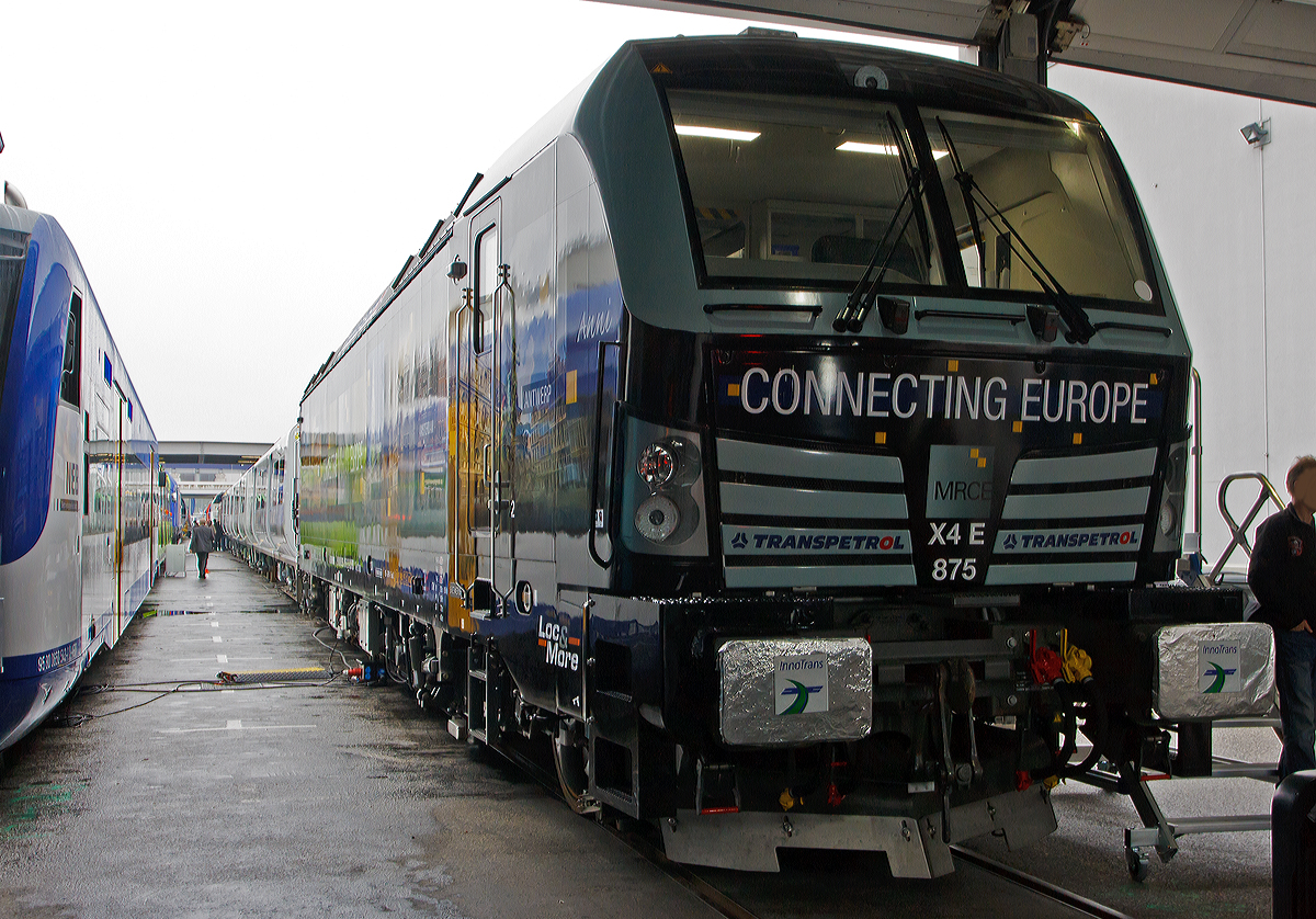 Die X4 E – 875   Anni   193 875-2  (91 80 6193 875-2 D-DISPO)  mit Werbung  Connecting Europe  der MRCE - Mitsui Rail Capital Europe GmbH, zurzeit vermietet an Transpetrol GmbH Internationale Eisenbahnspedition in Hamburg, wurde am Freigelände auf der Inno Trans 2014 in Berlin ausgestellt (hier 26.09.2014).  

Die Lok wurde 2014 von Siemens in München unter der Fabriknummer 21915 gebaut und an die MRCE geliefert. Die Vectron Lokomotive ist als AC – Lokomotive konzipiert mit 6.400 kW und zugelassen für Deutschland, Österreich und Ungarn inklusive ETCS, sie hat eine Höchstgeschwindigkeit von 200 km/h.
für Deutschland, Österreich und teilweise Ungarn, inklusive ETCS.

Technische Daten:
Spurweite: 1.435 mm
Achsformel: Bo'Bo'
Länge über Puffer: 18.980 mm
Drehzapfenabstand: 9.500 mm
Achsabstand im Drehgestell: 3.000 mm
Breite: 3.012 mm
Höhe:  4.248 mm
Raddurchmesser :  1.250 mm (neu) / 1.170 mm (abgenutzt)
Gewicht:  87 t
Spannungssysteme: 15 kV, 16,7 Hz und 25 kV, 50 Hz AC
Max. Leistung am Rad:  6.400 kW
Höchstgeschwindigkeit: 200 km/h
Anfahrzugskraft:  300 kN
Dauerzugkraft:  250 kN
Elektrische Bremskraft: 150 kN
Kraftübertragung: Ritzelhohlwellenantrieb
Lichtraumprofil: UIC 505-1