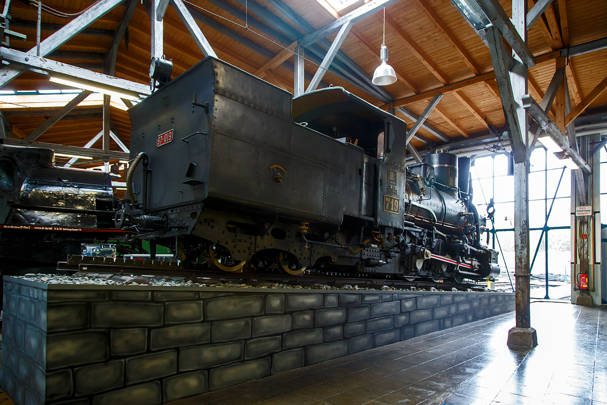 Die Zahnraddampflokomotive ex BHStB (Bosnisch-Herzegowinischen Staatsbahnen) / BHLB (Bosnisch-Herzegowinische Landesbahnen) IIIc5 719, ab 1918 SHS 719 (Železnice Kraljevine Srba, Hrvata i Slovenaca, deutsch Eisenbahnen des Königreichs der Serben, Kroaten und Slowenen, ab 1929 JDŽ 97-019 (Jugoslovenske Državne Železnice) und ab 1954 JŽ 97-019 (Jugoslovenske Železnice) am 11.09.2022 in der Lokwelt Freilassing.

Die Lok wurde 1908 von der Wiener Lokomotivfabrik Floridsdorf (WLF) für die Bosnisch-Herzegowinischen Staatsbahnen. Die WLF besaß die Lizenz des Zahnradbahn-Systems Abt für das Gebiet der damaligen Österreichisch-Ungarischen Monarchie. Die Außerdienststellung der Lok erfolgte erst Mitte der 1970er Jahre. Die Lok ist Eigentum vom Deutschen Museum – Verkehrszentrum.

Die österreichisch-ungarische Verwaltung erbaute nach der militärischen Okkupation der Provinz Bosnien-Herzegowina des osmanischen Reiches ein umfangreiches Schmalspurnetz mit der Spurweite von 760 mm. Bis 1908 agierte dieses Bahnnetz unter den Namen Bosnisch-Herzegowinische Staatsbahnen (BHStB), ab 1908 als „Bosnisch-Herzegowinische Landesbahnen (BHLB).

Die Zahnraddampflokomotiven der Reihe IIIc5 701–721 waren Stütztenderlokomotiven mit drei Kuppelachsen für Adhäsions- und Zahnradantrieb in Bosnischer Spurweite, beschafft von den Bosnisch-Herzegowinischen Staatsbahnen (BHStB). Der Zahnradantrieb (eigener zweizylindriger Antrieb) im System Abt (2 Lamellen) erfolgte durch zwei Zahnräder (Ø 688 mm). Die Nachfolgerinnen der BHStB, die Bosnisch-Herzegowinischen Landesbahnen (BHLB) und die Eisenbahnen des Königreichs Serbien, Kroatien und Slowenien (SHS) stellten weitere 17 Maschinen der Baureihe in Dienst. Bei den Jugoslawischen Eisenbahnen (JDŽ, später JŽ) wurde die Serie als Baureihe 97 bezeichnet. Sie ist mit 38 Exemplaren die in größter Stückzahl gebaute Zahnradlokomotive der Welt.

Die Reihe IIIc5 ist als Weiterentwicklung der IIIb4 konstruktiv stark an ihre Vorgängerin angelehnt. Die schmale Bosnische Spurweite machte bei beiden Typen die Verwendung eines Außenrahmens notwendig, in dem die drei gekuppelten Treibachsen gelagert sind. Wie bei den von der Lokomotivfabrik Floridsdorf stammenden Zahnradlokomotiven üblich ist der Zahnradantrieb als Innentriebwerk innerhalb des Lokomotivrahmens ausgebildet. Sowohl die außenliegende Steuerung für den Adhäsionsantrieb als auch diejenige für den Zahnradantrieb waren nach dem System Joy ausgeführt.

Für eine gefahrlose Talfahrt stehen fünf voneinander unabhängigen Bremssysteme zur Verfügung:
• Eine auf die zweite und dritte Adhäsionssachse wirkende mechanische Bremse, die mit Handkurbel und Spindel im Führerstand angezogen wird
• Auf die Zahnradachsen wirkende Bandbremsen, die auch mit Handkurbel und Spindel vom Führerstand aus bedient werden
• Die Gegendruckbremse des Adhäsionstriebwerks
• Gegendruckbremse der Zahnradantriebs, die zusammen mit der Gegendruckbremse des Adhäsionsantriebs als verschleißfreie 
• Die auf den Stütztender und die angehängten Wagen wirkende Vakuumbremse. 

Die Loks sind für den Betrieb mit einer zweilamelligen Zahnstange der Bauart Abt ausgerüstet. Der Zahnradantrieb der 2 Zahnräder verfügt über einen eigenen zweizylindrigen Antrieb, welcher unter der Rauchkammer, zwischen den beiden Zylindern des Adhäsionstriebwerks angebracht ist. Beide Triebwerke können getrennt von einander angesteuert werden.

Die Unterbringung der Wasser- und Kohlevorräte erfolgt in einem zweiachsigen „Stütztender“, der fest mit der Maschine gekoppelt ist und den hinteren Teil der Lokmotive trägt.

TECHNISCHE DATEN:
Gebaute Anzahl: 38
Hersteller:  Wiener Lokomotivfabrik Floridsdorf (WLF)
Baujahre:  1894–1919
Bauart: Czz2’t
Gattung: 33.8
Spurweite:  760 mm (Bosnische Spur)
Länge über Kupplung: 10.143 mm
Gesamtradstand: 6840 mm
Dienstgewicht: 36,5 bis 37,46 t (diese hier 36,8 t)
Höchstgeschwindigkeit: 30 km/h
Indizierte Leistung: 300 PS (ca. 220 kW)
Anfahrzugkraft:  80 kN
Kuppelraddurchmesser: 800 mm
Laufraddurchmesser: 650 mm
Zahnradsystem:  Abt (2 Lamellen)
Zahnraddurchmesser:  688 mm
Zylinderdurchmesser:  340 mm
Kolbenhub: 450 mm
Zylinderdurchmesser Zahnradantrieb: 360 mm
Kolbenhub Zahnradantrieb:  360 mm
Kesselüberdruck: 12 bar
Rostfläche: 1,58 bis 1,66 m²
Verdampfungsheizfläche: 89,0 m²
Tender: Stütztender
Wasservorrat: 3,5 m³
Brennstoffvorrat: 3,5 t

Die Nachbestellungen erfolgten ohne wesentliche Änderungen. Der Zahnradrahmen wurde durch höhere Barren verstärkt. Von der zweiten Lieferung an wurde die Rostfläche auf 1,58 m² verringert und die Radstände etwas verkleinert. Ab der dritten Teilserie wurde die Kühlwassermenge der Gegendruckbremsen von 0,4 auf 0,55 m³ erhöht. Die letzte Lieferung erhielt Abdampfvorwärmer Bauart Knorr. Durch die Änderungen veränderte sich das Gewicht. Bei den ersten Lokomotiven betrug das Leergewicht 27,2 t, bei der letzten Teilserie 29,09 t.