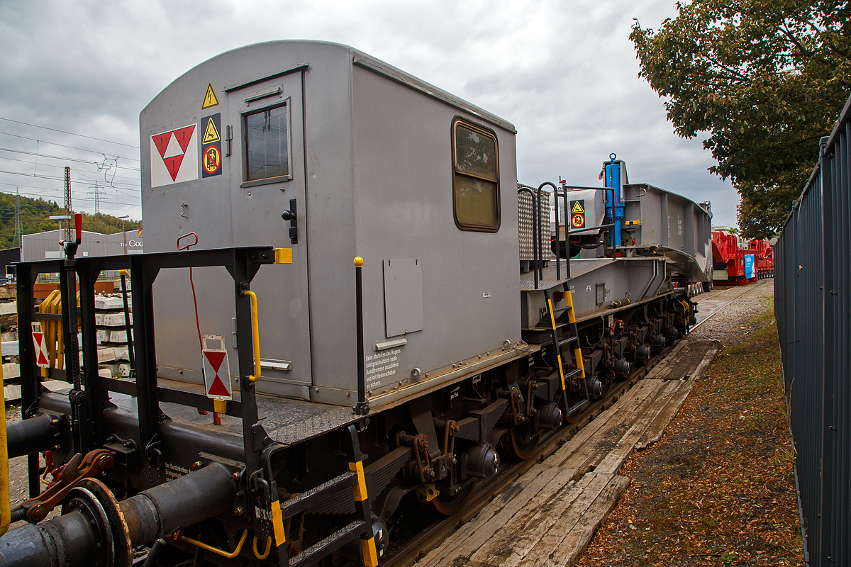 Eine Hälfte des 20-achsigern Tragschnabelwagen der Gattung Uaai 687.9 (84 80 9960 003-5 D-AMPR) der Amprion GmbH abgestellt am 03.10.2021 in Kreuztal auf dem Betriebsgelände der KAF (fotografiert vom Gehweg durch den Zaun). Der Trafo war bereits (oder war noch) auf einer Scherenhub-Kesselbrücken der Kahl Schwerlast GmbH verladen, dies kann man im Hintergrund sehen.

Die Amprion GmbH ist ein deutscher Übertragungsnetzbetreiber für den Strombereich. Das Unternehmen, welches als Teil des RWE-Konzerns entstand, beschäftigt etwa 1100 Mitarbeiter, sein Hauptsitz befindet sich in Dortmund.

Der Tragschnabelwagen wurde 1961 bei MAN unter der Fabriknummer 146523 gebaut. Es wurden 3 Stück der Bauart Uaai 687.9 hergestellt.

TECHNISCHE DATEN:
Spurweite: 1.435 mm (Normalspur)
Anzahl der Achsen: 20 in 4 Drehgestellen á 5 Achsen
Gattung/Bauart: Uaai 687.9
Länge über Puffer: 32.070 mm (Leerfahrt) / 41.140 mm (mit Trafo)
Drehzapfenabstand 1: 15.886 mm (Leerfahrt) / 24.956 mm (mit Trafo)
Drehzapfenabstand 2 (zw. den DG1+2 / DG 3+4): 7.500 mm
Achsabstand in den Drehgestellen: 4 x 1.500 mm = 6.000 mm
Laufraddurchmesser: 1.000 mm (neu)
Eigengewicht: 117 t
Maximale Ladegewicht: 250 t
Achsdruck: 5,85 t (Leerfahrt) / 18,35 t (mit Trafo)
Meterlast: 3,65 t/m (Leerfahrt) / 8,92 t/m (mit Trafo)
Höchstgeschwindigkeit: 90 km/h (Leerfahrt) / 40 km/h (Beladen)
Kleinster befahrbarer Gleisbogenhalbmesser: 75 m
Tragende Bauteile gefertigt aus: M St 52-3
Bremse: KE-G (LL)
Bremssohle: IP 116
Bauart der Handbremse: bodenbedienbare Handbremse 2 x 45 t