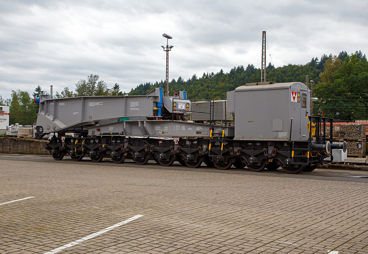 Eine Hälfte des 20-achsigern Tragschnabelwagen der Gattung Uaai 687.9 (84 80 9960 003-5 D-AMPR) der Amprion GmbH abgestellt am 03.10.2021 in Kreuztal auf dem Betriebsgelände der KAF (fotografiert vom Gehweg durch den Zaun). Der Trafo war bereits (oder war noch) auf einer Scherenhub-Kesselbrücken der Kahl Schwerlast GmbH verladen.

Die Amprion GmbH ist ein deutscher Übertragungsnetzbetreiber für den Strombereich. Das Unternehmen, welches als Teil des RWE-Konzerns entstand, beschäftigt etwa 1100 Mitarbeiter, sein Hauptsitz befindet sich in Dortmund.

Der Tragschnabelwagen wurde 1961 bei MAN unter der Fabriknummer 146523 gebaut. Es wurden 3 Stück der Bauart Uaai 687.9 hergestellt.

TECHNISCHE DATEN:
Spurweite: 1.435 mm (Normalspur)
Anzahl der Achsen: 20 in 4 Drehgestellen á 5 Achsen
Gattung/Bauart: Uaai 687.9
Länge über Puffer: 32.070 mm (Leerfahrt) / 41.140 mm (mit Trafo)
Drehzapfenabstand 1: 15.886 mm (Leerfahrt) / 24.956 mm (mit Trafo)
Drehzapfenabstand 2 (zw. den DG1+2 / DG 3+4): 7.500 mm
Achsabstand in den Drehgestellen: 4 x 1.500 mm = 6.000 mm
Laufraddurchmesser: 1.000 mm (neu)
Eigengewicht: 117 t
Maximale Ladegewicht: 250 t
Achsdruck: 5,85 t (Leerfahrt) / 18,35 t (mit Trafo)
Meterlast: 3,65 t/m (Leerfahrt) / 8,92 t/m (mit Trafo)
Höchstgeschwindigkeit: 90 km/h (Leerfahrt) / 40 km/h (Beladen)
Kleinster befahrbarer Gleisbogenhalbmesser: 75 m
Tragende Bauteile gefertigt aus: M St 52-3
Bremse: KE-G (LL)
Bremssohle: IP 116
Bauart der Handbremse: bodenbedienbare Handbremse 2 x 45 t