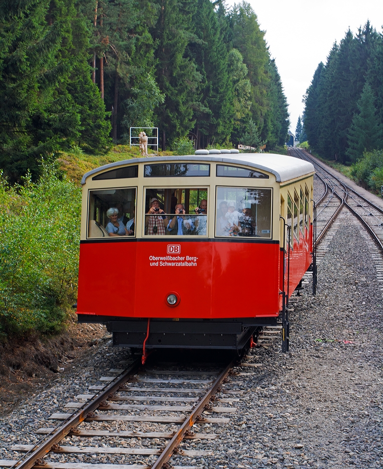 Fahrt mit der Oberwei�bacher Bergbahn am 24.08.2013, der Wagen 1 - der Personenwagen der Standseilbahn befindet sich auf Talfahrt und kommt uns in der Mitte (zwischen Obstfelderschmiede und Lichtenhain) entgegen.

Der Personenwagen, im betrieblichen Umgang als Wagen 1 bezeichnet, ist seit der Er�ffnung 1923 nur an den Stirnseiten leicht ver�ndert worden. Das erfolgte 1959, als er gr��ere Stirnfenster erhielt und die leicht ausgestellte Stirnpartie. Bei der Rekonstruktion  2002 wurde die Fahrradb�hne angebaut. Besonderheit, sie ist nur am Fahrgestell befestigt und kann 8 Fahrr�der aufnehmen.

Bergbahntechnik einer ganz besonderen Standseilbahn
Die Bergbahn besteht aus zwei Teilen:
- der Standseilbahn, von Obstfelderschmiede nach Lichtenhain und
- der  Flachstrecke  der Bergbahn, von Lichtenhain nach Cursdorf

Die Konzession zum Bau wurde f�r eine Eisenbahnstrecke von Obstfelderschmiede nach Cursdorf erteilt, heute als Strecke Nr. 6691, KBS 563, der Deutschen Bahn AG gef�hrt. Die Standseilbahn ist also ein Bestandteil dieser Eisenbahnstrecke.
 Die Standseilbahn hat zwei unterschiedliche Fahrzeuge, einen “Personenwagen” und eine “G�terb�hne” zum Transport normalspuriger Eisenbahnwagen bis 27 t Gesamtmasse.
Sie wurde gebaut f�r den G�terverkehr, um die Hochebene um Oberwei�bach an das deutsche Eisenbahn-Netz anzuschlie�en.
 
Statt G�terwagen, ist heute in der Regel ein ehemaliger Triebwagen-Beiwagen oder das  Cabrio , ein offener Wagen, auf der G�terb�hne aufgesetzt.
Die  Strecke ist eingleisig und hat eine Abt´sche Ausweiche in der Mitte, wo beide Wagen aneinander vorbei fahren. Eine weitere Abt’sche Weiche in der Talstation trennt die Strecke in zwei Gleise, um den Personenwagen an den Bahnsteig und die G�terb�hne an die Verladerampe zu leiten.
Die Standseilbahn hat an beiden Enden jeweils Anschlu� �ber eine Drehscheibe an die Bahnanlagen mit Regelspur-Gleisen.

Quelle: http://www.oberweissbacher-bergbahn.com/de/obs-info
