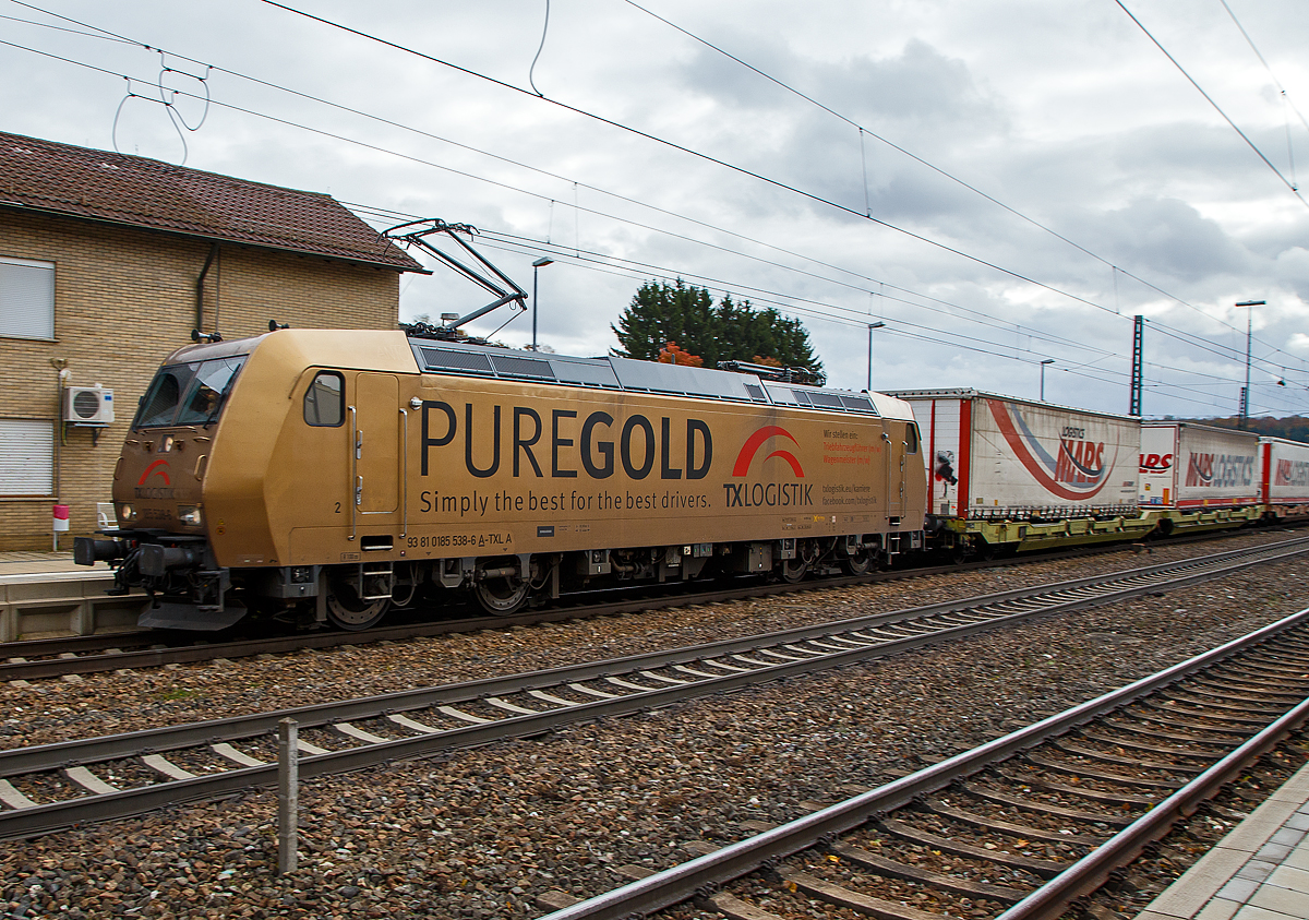 Hier nochmal von der Seite....
Die TX Logistik 185 538-6 (93 81 0185 538-6 A-TXLA, ex 91 80 6185 538-6 D-TXL) f�hrt am 26.10.2021 mit einem langen KLV-Zug durch den Bahnhof Amstetten (W�rtt) in Richtung Stuttgart. Gleich geht es die ber�hmte Geislinger Steige hinab. 

Nochmal einen liebe Gru� an den netten Lokf�hrer zur�ck, der mich hier mit Lichthupe gr��te.

Die TRAXX F140 AC wurde 2004 bei Bombardier in Kassel unter der Fabriknummer 33657 gebaut. Sie hat die Zulassungen f�r Deutschland und �sterreich. Die Lok tr�gt die Werbung PUREGOLD f�r die TX Logistik.