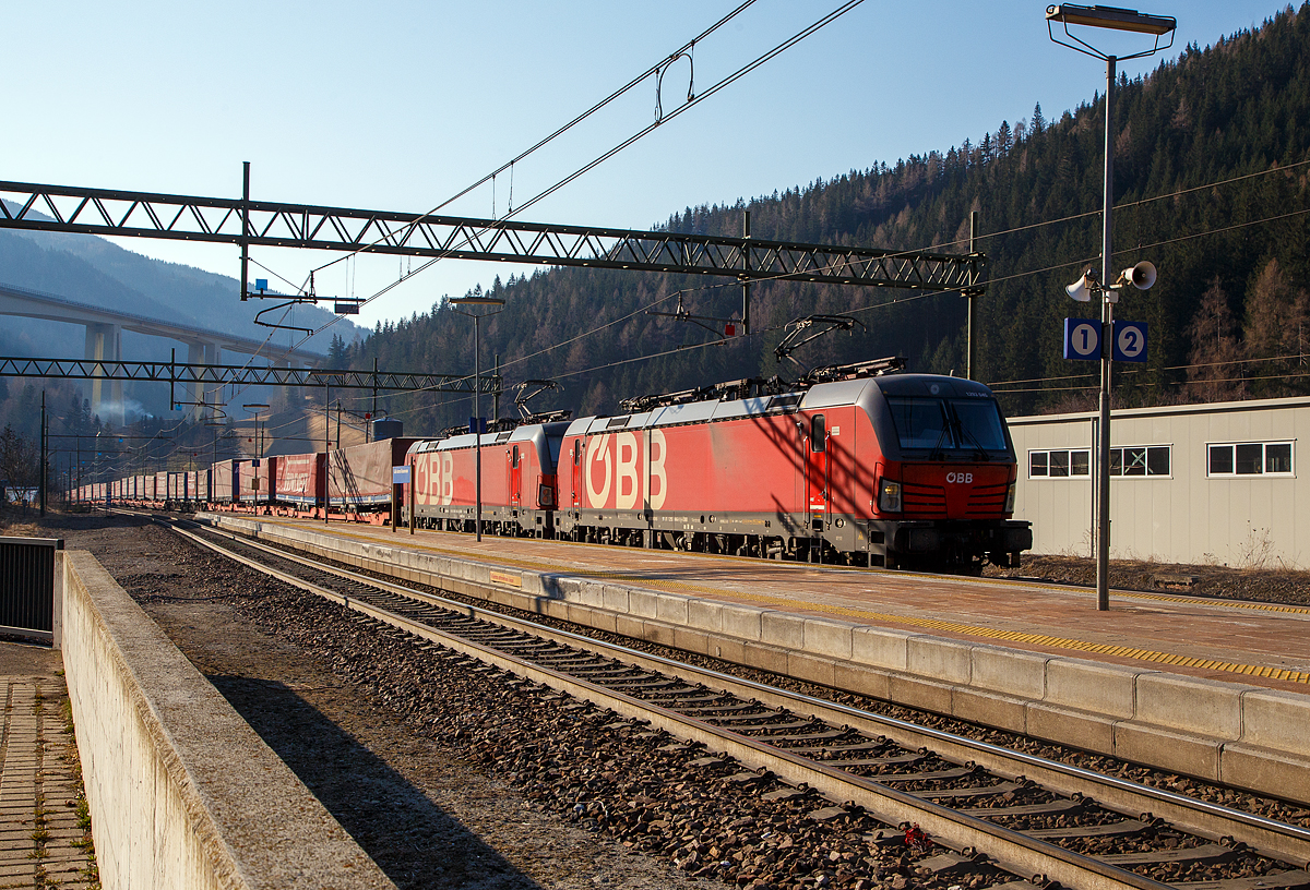 In Doppeltraktion fahren die beiden �BB Vectron MS 1293 046-9 und 1293 035-2 am 27.03.2022 mit einem langen „Winner“-KLV-Zug durch den Bahnhof Gossensa�/Colle Isarco zum Brenner/Brennero hinauf.

Im Hintergrund das Wipptal �berbr�ckende Gossensa�-Viadukt (Viadotto Colle Isarco) der Brennerautobahn. Noch fahren auf der Brennerautobahn teilweise LKW an LKW, mit der 2032 geplanten Er�ffnung von dem 64 km langen Brennerbasistunnel (BBT), soll dies dann vorbei sein. Dann ist man mit der Bahn von M�nchen viel schneller in Verona oder Venedig, aber dann ist f�r uns Bahnfotografen auch nichts mehr viel los auf der Brennerbahn (Ferrovia del Brennero).
