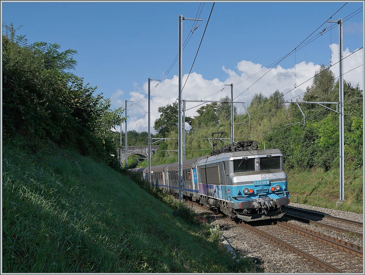 Kurz vor der Steinbogenbrücke, die sich auf dem halben Weg zwischen Satigny und Russin befindet und im Hintergrund erkennbar ist, schiebt die SNCF BB 22360  Nez cassé  ihren TER in Richtung Lyon.

2. August 2021