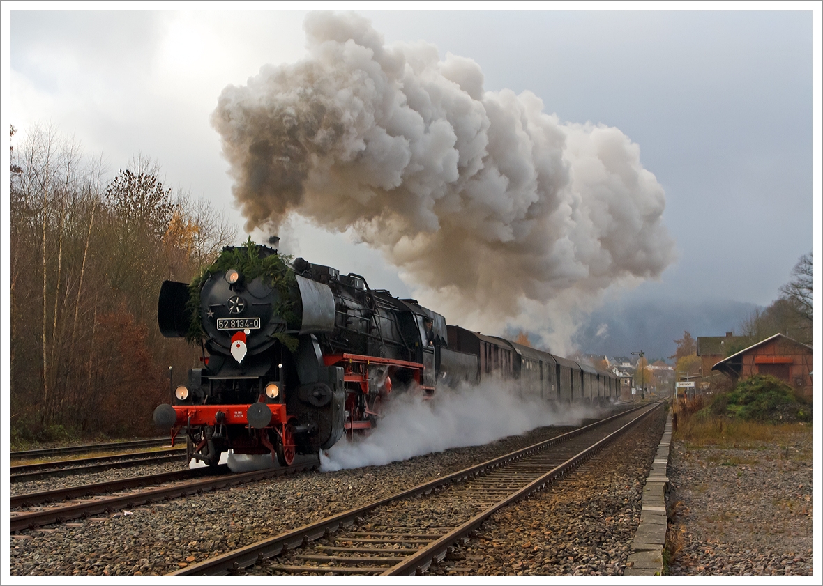 
Mit mächtiger Rauchfahne durchfährt die Betzdorfer 52 8134-0 am 01.12.2013 Herdorf, hier kurz hinter dem Bahnhof. Heute veranstalten die Eisenbahnfreunden Betzdorf ihre alljährlichen Nikolausfahrten zwischen Betzdorf/Sieg und Würgendorf.

 Die Lok war, bedingt durch die Wiedervereinigung, eine der letzten Normalspurigen Dampfloks der DB.  Zudem war sie als 052 134-4 die einzige wahre 52 der DB (BR 52.80). Die Lok wurde 1965 aus der 1943 bei der Lokfabrik Wien-Floridsdorf (Fabriknummer 16591) gebauten 52 7138 rekonstruiert.
