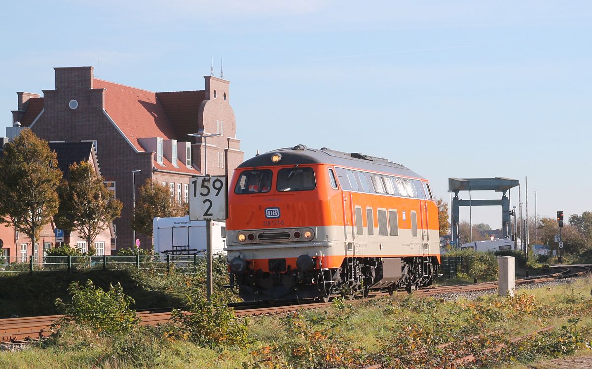 NeSA 218 117 fährt zu dem Schienenschleifzug, den sie nach Lübeck bringen soll, im Hintergrund die Klappbrücke über den Husumer Hafen, 28.10.2021