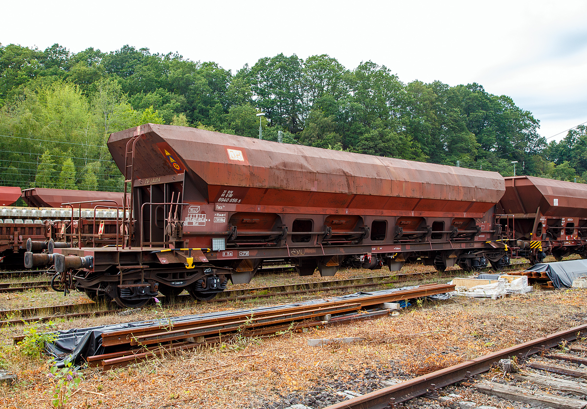 Offener Drehgestell-Schüttgutwagen mit dosierbarer Schwerkraftentladung und vier Radsätzen, 31 80 6941 656-5 D-DB, Gattung Facs 124, der DB Cargo Deutschland AG, abgestellt am 09.08.2019 in Betzdorf/Sieg.

Die DR ließ zwischen 1978 und 1980 bei ANF Industrie (Frankreich) über 1.450 vierachsige offene Selbstentladewagen mit vier Kammern bauen, die zunächst als Eads-y (5970) eingereiht werden. Bei der DB AG werden die Wagen 1994 in Facs 124 umgezeichnet.

Bei den offenen Selbstentladewagen hat der Laderaum die Form mehrerer nebeneinander stehender Trichter. Der Entladevorgang erfolgt über die Schwerkraft des Ladegutes.
Mehrere Auslauföffnungen mit Drehschiebern ermöglichen die restlose Entladung des Wagens nach der einen oder anderen Seite. Die Menge ist regulierbar - so wie es zum Beispiel für die Entladung über Förderband erforderlich ist. Geeignet sind die Wagen für den Transport nicht nässeempfindlicher Güter in loser Schüttung. Die Drehschieber über einer Einrichtung auf der Bühne an einer Stirnseite des Wagens können einzeln bedient werden.

Der Wagen ist für den Transport von Nässe unempfindlichen Schüttgütern vorgesehen. Das Untergestell besteht aus miteinander verschweißten Blechen und Walzprofilen. Der Wagenkasten ist eine Schweißkonstruktion und besteht aus vier Trichtern. Querrippen teilen den Wagenkasten in vier Räume, von denen jeder an seinem Unterteil zwei Entladeöffnungen aufweist, die sich an beiden Seiten der horizontalen Mittellinie des Wagens befinden. Über jeder Entladeöffnung ist am Kastenblech eine Stütze für einen Vibrator angeschraubt.
Die acht kreisförmig ausgebildeten Wölbschieber sind auf Rollen gelagert und verschieben sich auf Laufbahnen, die außerhalb der Rinnen angebracht sind. Unter jeder Entladeöffnung sind eine feste und eine schwenkbare Auslaufrutsche angeordnet. Die schwenkbaren Auslaufrutschen werden einzeln durch einen Hebel betätigt, der in der Nähe der Rutsche angebracht ist. Die Betätigung der Wölbschieber erfolgt von der Bedienungsplattform aus. Die Entladung des Wagens erfolgt nach Öffnen der Schieber durch die Schwerkraft des Ladegutes. Für den Zugang zur Bedienungsplattform sind zwei Auftritte mit Gitterrosten (500 x 160 mm) vorhanden.

Das Entfernen von Ladegutresten in der Be- oder Entladestraße ist nur durch leichte Gummihammerschläge auf die äußeren Behälterwandungen gestattet oder durch den Einsatz von Pressluftlanzen im Laderaum! 

TECHNISCHE DATEN:
Hersteller: ANF Industrie (Frankreich)
Spurweite: 1.435 mm
Achsanzahl: 4 (in 2 Drehgestellen)
Länge über Puffer: 19.040 mm
Drehzapfenabstand: 14.000 mm
Achsabstand im Drehgestell: 1.800 mm
Größe der Beladeöffnung: 1.800 x 15.300 mm
Laderaum:  70 m³
Breite der festen Auslaufrutschen: 600 mm
Breite der schwenkbaren Auslaufrutschen: 476 mm
Wagenhöhe:  4.000 mm
Höchstgeschwindigkeit: 100 km/h (beladen) / 120 km/h (leer)
Maximales Ladegewicht: 56,0 t (ab Streckenklasse C)
Eigengewicht: 23.890 kg
Drehgestell-Bauart: Y 25 Cs – 639
Kleinster bef. Gleisbogenradius: 75 m
Bauart der Bremse:  KE-GP
Intern. Verwendungsfähigkeit: RIV
