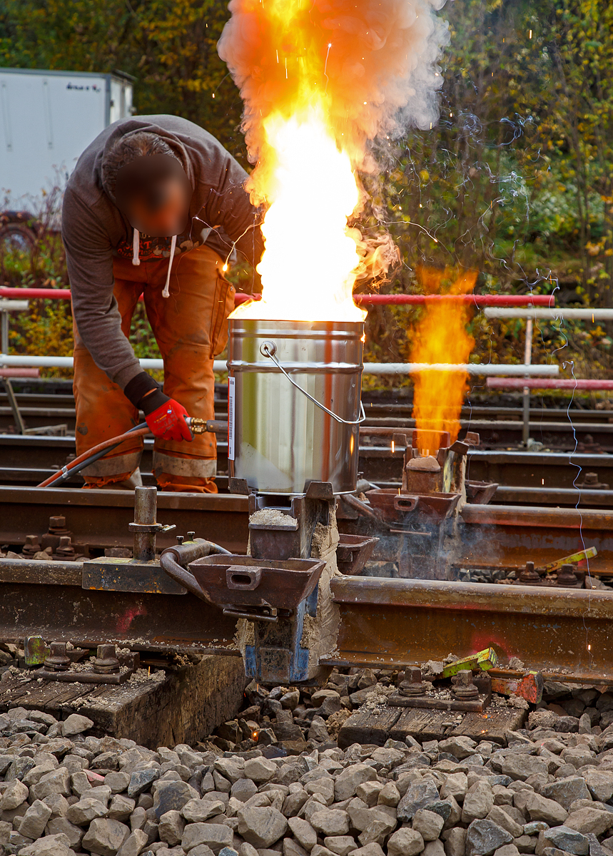 
Thermitschweißen am 31.10.2020 an der Hellertalbahn (KBS 462 / DB-Streckennummer 2651) hier Gleis 1 vom Bahnhof Herdorf.

Bild 3 – Der Reaktionstiegel ist auf die Form aufgesetzt und mit einem Anzünder entzündet, so startet nun die Thermit­Reaktion. Gleichzeitig wird nun der nebenliegende Schweißstoß vorgewärmt.
