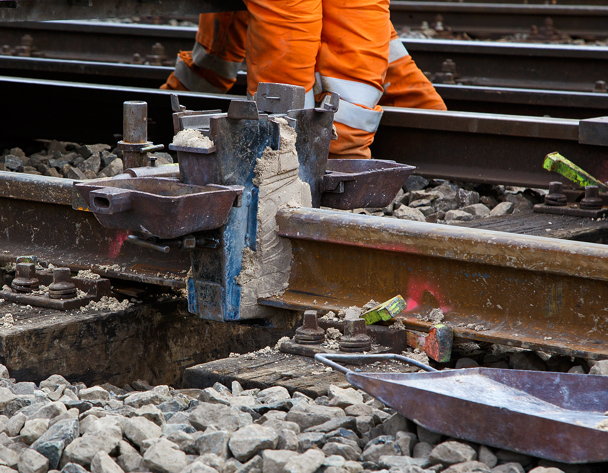 
Thermitschweißen am 31.10.2020 an der Hellertalbahn (KBS 462 / DB-Streckennummer 2651) hier Gleis 1 vom Bahnhof Herdorf.

Bild 1 - Die Gießform (Formhalteblech und Form) ist montiert und abgedichtet. Rechts und links am Formhalteblech sind die Schlackenschalen angehangen.
