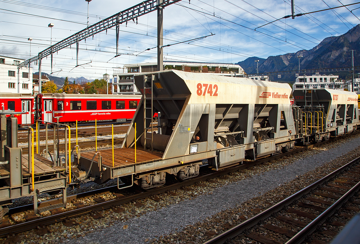 Vierachsiger Schmalspur Drehgestell-Schotterwagen (Schwerkraftentladewagen) Xac der Serie 8726 – 8742 (hier Xac 8742, ex Fac 8742)  eingereiht in einen Bauzug am 01.11.2019 im Rbf Chur (aufgenommen aus einem Zug heraus). Diese Wagen wurden 1997 von der Firma Josef Meyer in Rheinfelden gebaut, sp�ter erfolgte ein Umbau zum Dienstwagen Xac 8742.

Mit den Schwerkraftentladewagen transportiert die RhB problemlos Ihre Sch�ttg�ter wie Kies, Sand etc. auf der Schiene durch Graub�nden. Ein rascher Verlad und Entlad spart Zeit und Geld und mit 33 – 34 Tonnen Ladung ist es eine gewichtige Alternative zum Stra�entransport.

TECHNISCHE DATEN:
Spurweite: 1.000 mm
L�nge �ber Puffer: 12.500 mm
Breite �ber Alles: 2.550 mm
H�he �ber SOK: 3.360 mm
Drehzapfenabstand: 7.000 mm 
Achsabstand im Drehgestell: 1.400 mm
Laufraddurchmesser: 750 mm (neu)
Breite der Entlade�ffnungen: 2 x 1.232 mm
Eigengewicht: 15.430 kg
Ladegewicht: max. 33 t
Ladevolumen: 22 m�
