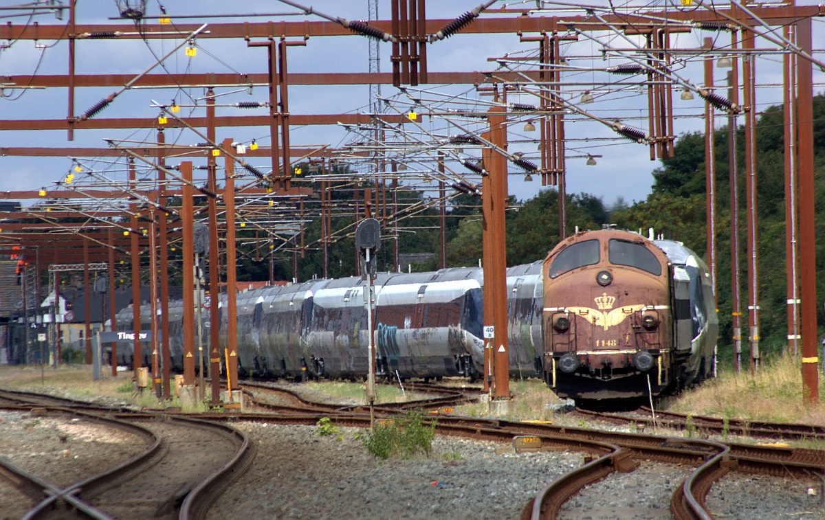 Vom Bahn�bergang in Tinglev aus aufgenommen...SRP Litra MY 1148 mit ihrem Zug bestehend aus RailAdv Habfis + 9x IC2 + RailAdv Habfis in Warteposition am Bhf in Tinglev. 08.08.2022