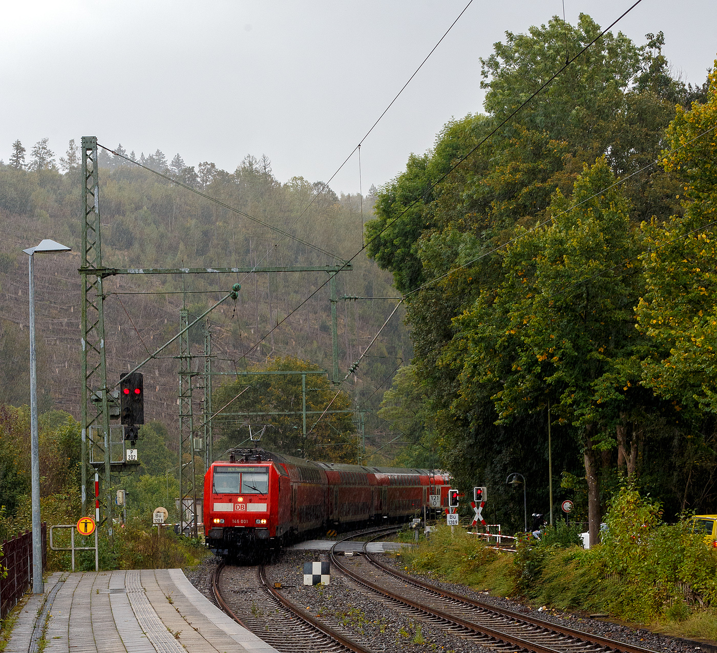 Bei einem kurzen starken Regenguss, erreicht die 146 001-3 (91 80 6146 001-3 D-DB) der DB Regio NRW am 28 September  2024, mit dem RE 9 (rsx - Rhein-Sieg-Express) Aachen - K�ln – Siegen, den Bahnhof Kirchen/Sieg.

Die TRAXX P160 AC1 (Br 146.0) wurde 2000 von ABB Daimler-Benz Transportation GmbH (Adtranz) in Kassel unter der Fabriknummer 33808 gebaut.  
