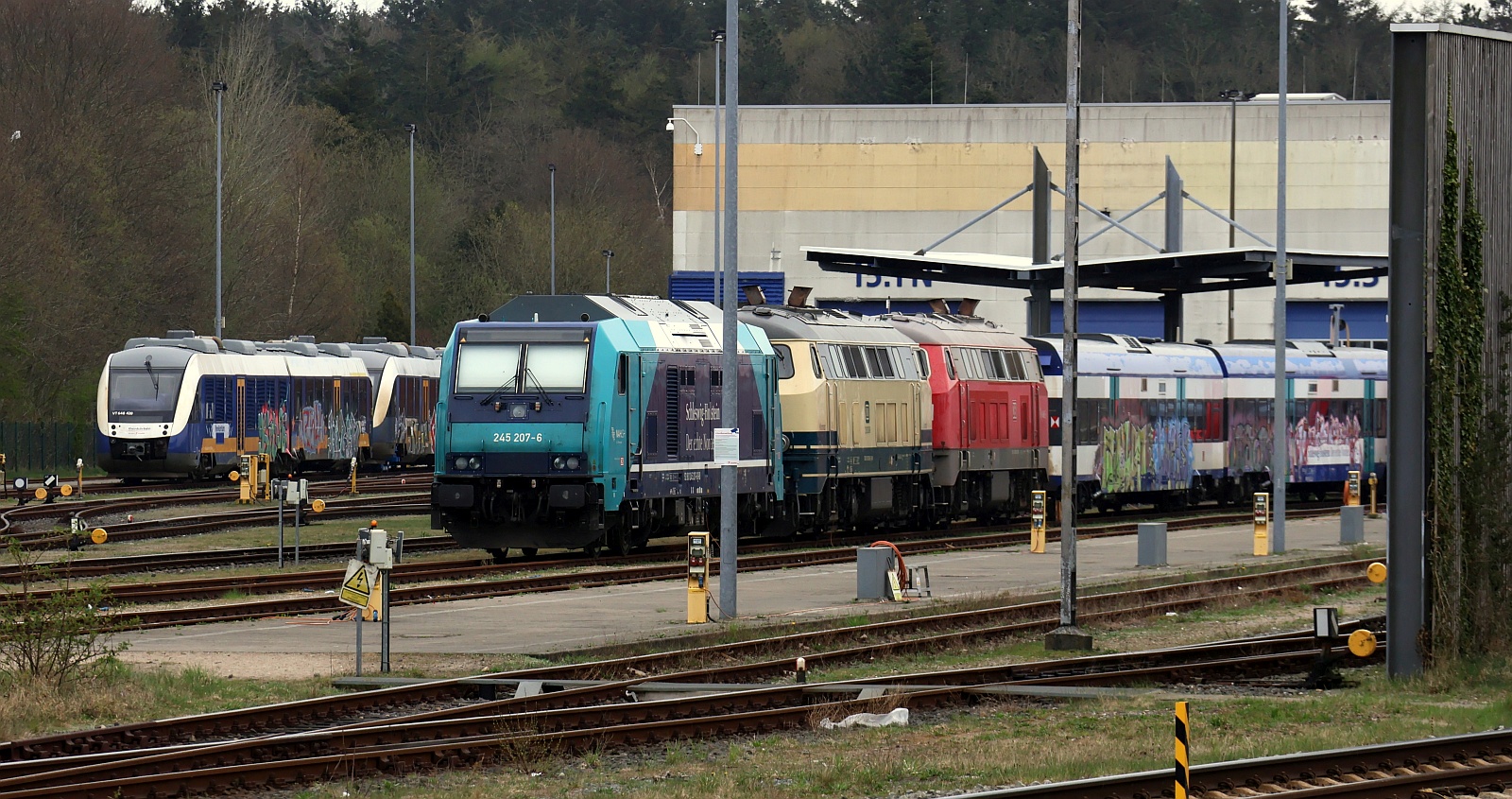 Blick auf das Bw in Husum: vlnr RheinRuhr Bahn 648 420/920+ 648 4xx mit aufgebockter Vorderachse, NAH.SH/DB 245 207, 218 330 + 218 470 sowie einige beschmierte MP Wagen. Husum 13.04.2025