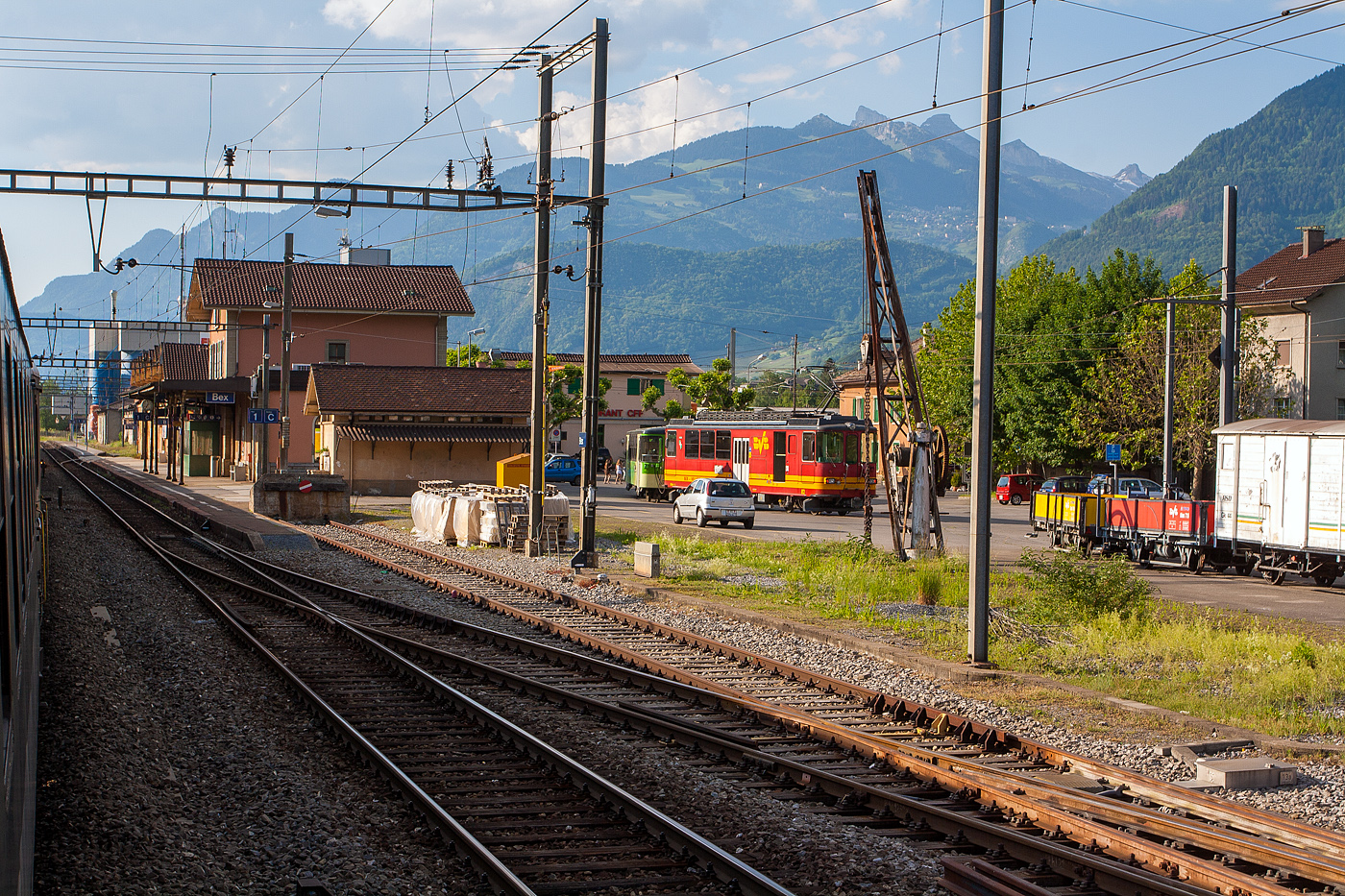 Blick aus unseren SBB Zug heraus am 28 Mai 2012 auf dem Bahnhof Bex, damals konnte man die Fenster noch �ffnen. 

Am Bahnhofsvorplatz steht der tpc BVB BDeh 4/4 82 „Ollon“, ein elektrischer Personentriebwagen mit Gep�ckabteil f�r den gemischtem Adh�sions- und Zahnradbetrieb, noch in originaler Farbgebung, mit einem Pendelzug. Damals gingen die Gleise vom Bahnhof nach links Richtung G�terschuppen. Die Wagen vom Pendelzug (Steuerwagen und der Zwischenwagen B 62) hatten schon die neue gr�ne TPC-Farbgebung.