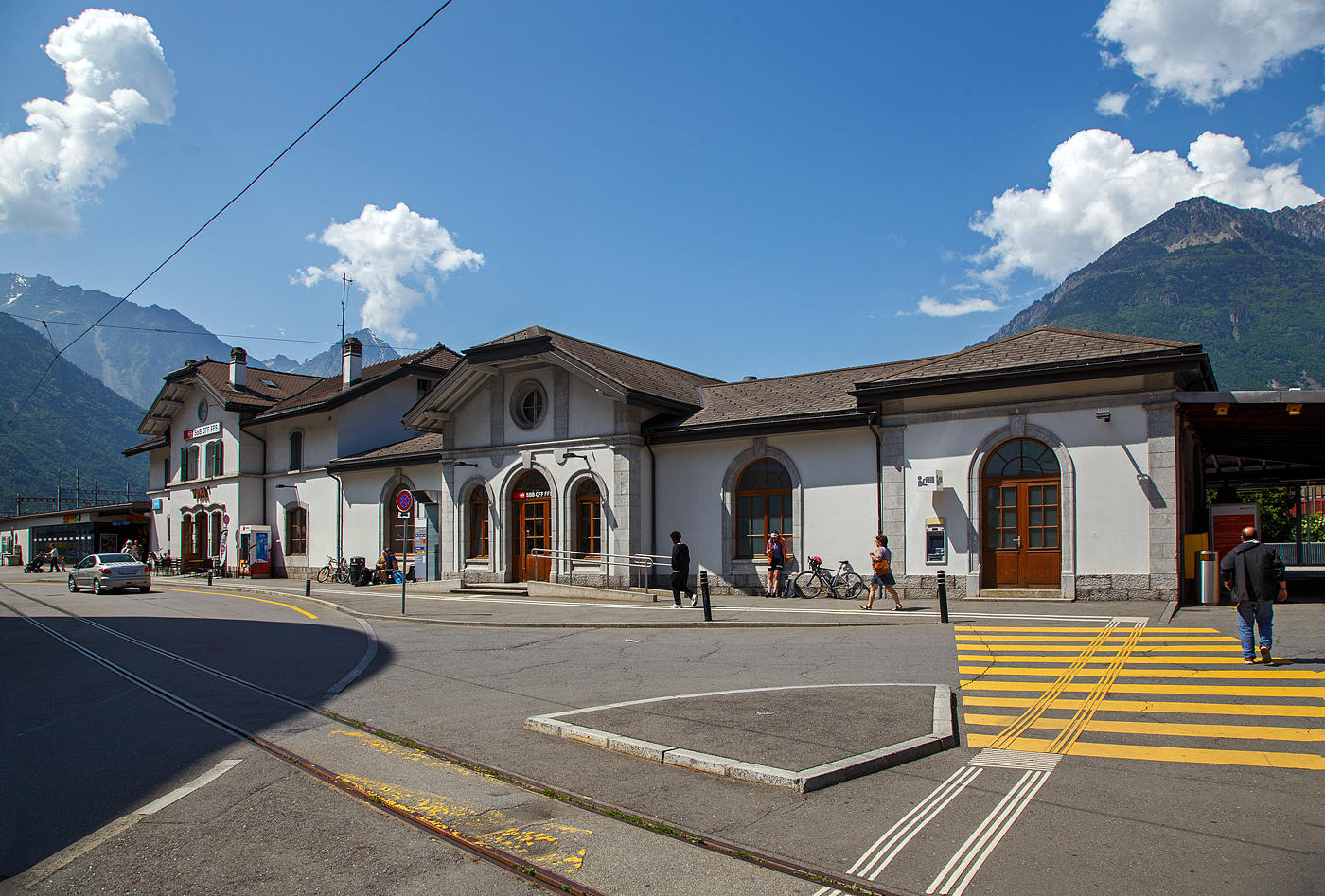 Das Empfangsgeb�ude vom SBB Bahnhof Martigny (deutsch Martinach) am 26.05.2023, vom Vorplatz gesehen.

Hier links vom Geb�ude (nicht im Bild) ist der schmalspurige Bahnhof (Gleis 40 und 41) der TMR - Transports de Martigny et R�gions, ex Martigny-Ch�telard-Bahn (MC), f�r den „Mont-Blanc Express“. Von wo man via Ch�telard nach Vallorcine (F) fahren kann. Von Vallorcine kann man dann mit der SNCF (auch schmalspurig) die weiterf�hrende Bahnstrecke via Chamonix-Mont-Blanc nach Saint-Gervais weiterfahren.

Im Vordergrund das schmalspurige Gleis vom TMR Bahnhof zur Remise. 